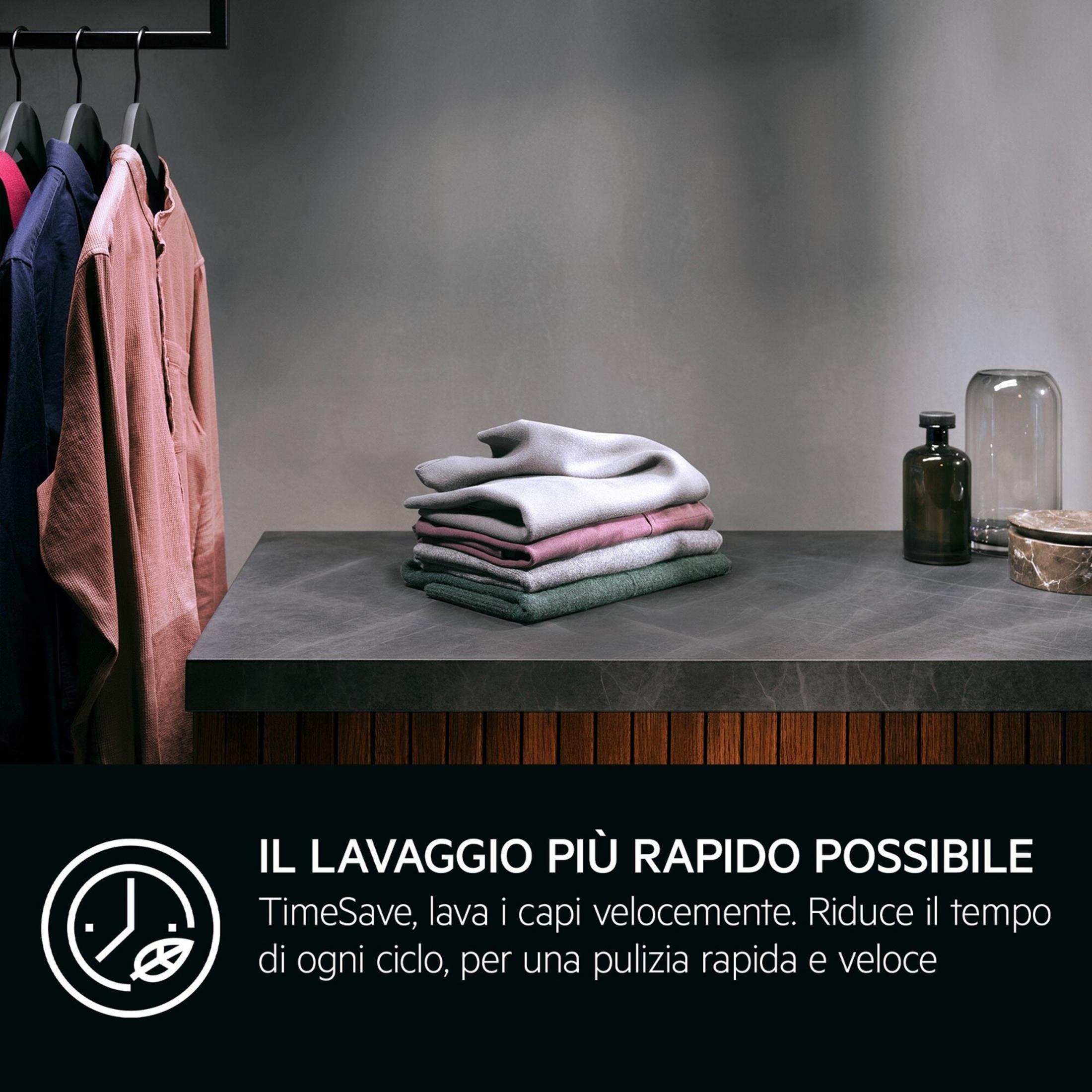 Vestiti appesi su grucce, tessuti accatastati su un tavolo.