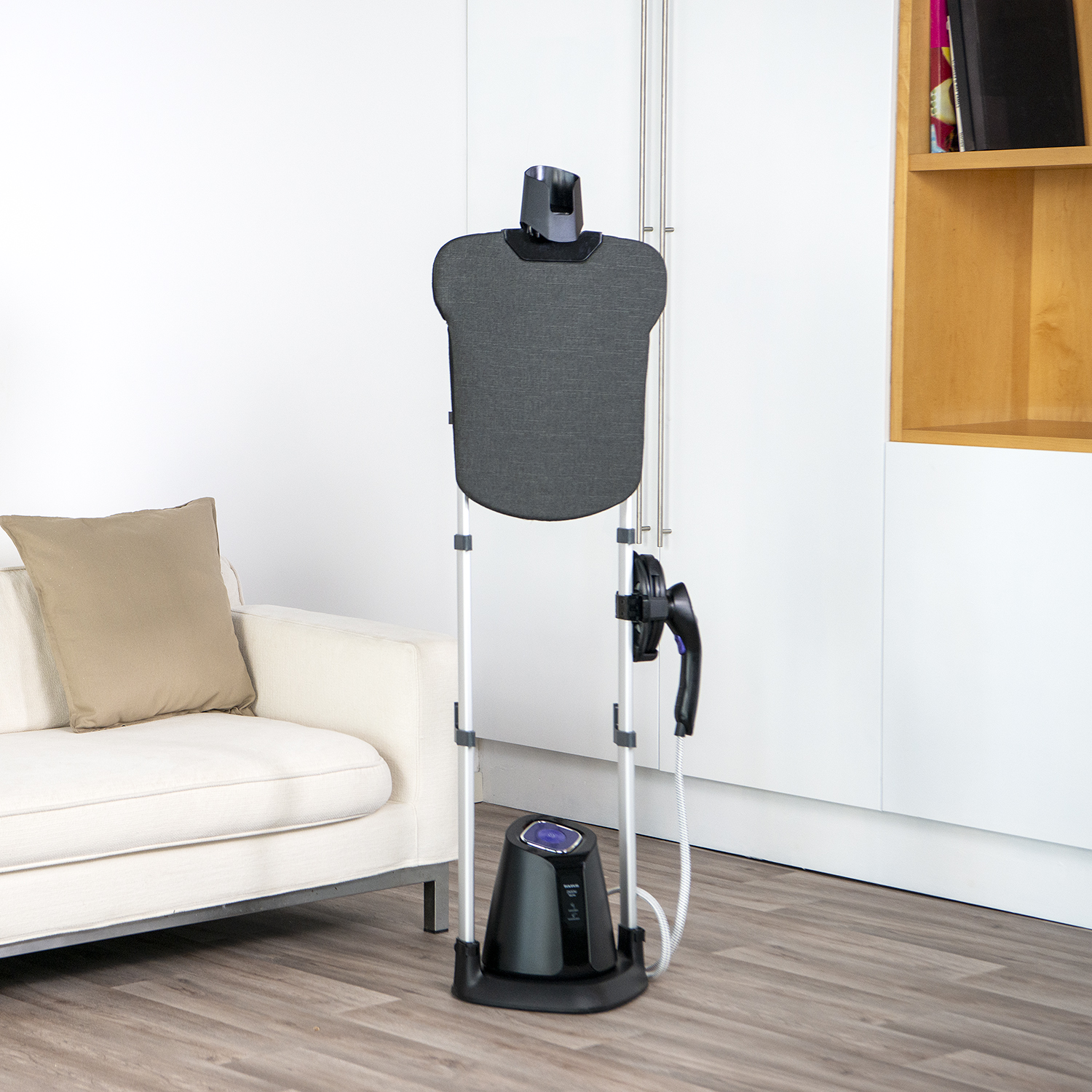 Un vaporizador de ropa está junto a un sofá blanco en una habitación.