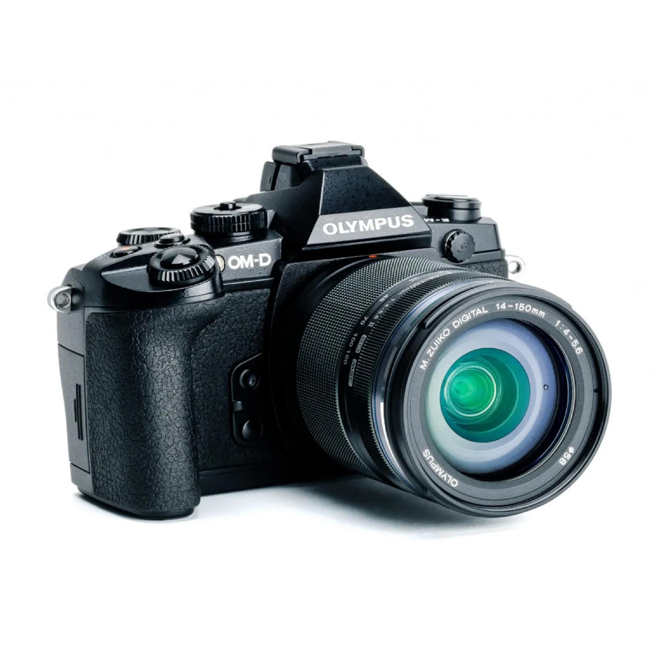 Fotocamera Olympus OM-D nera con obiettivo 14-150mm attaccato su sfondo bianco.