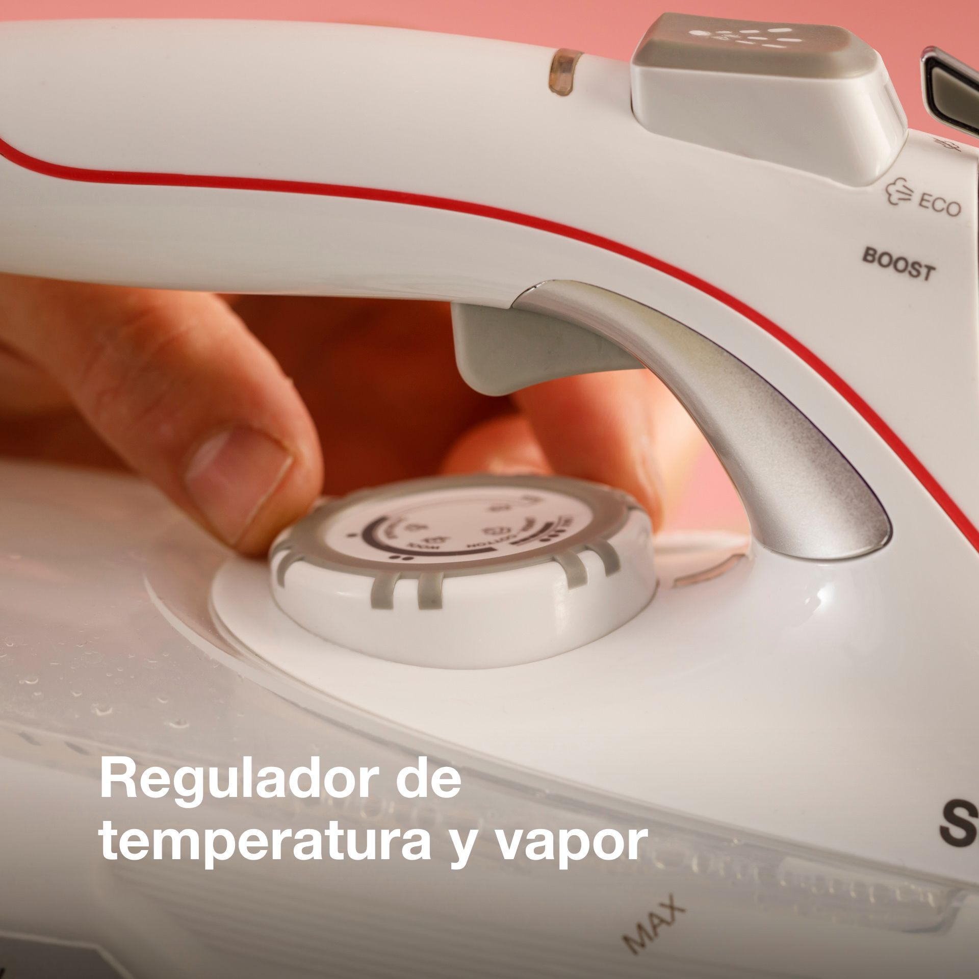 Una mano gira un dial de temperatura en una plancha blanca con detalles rojos.