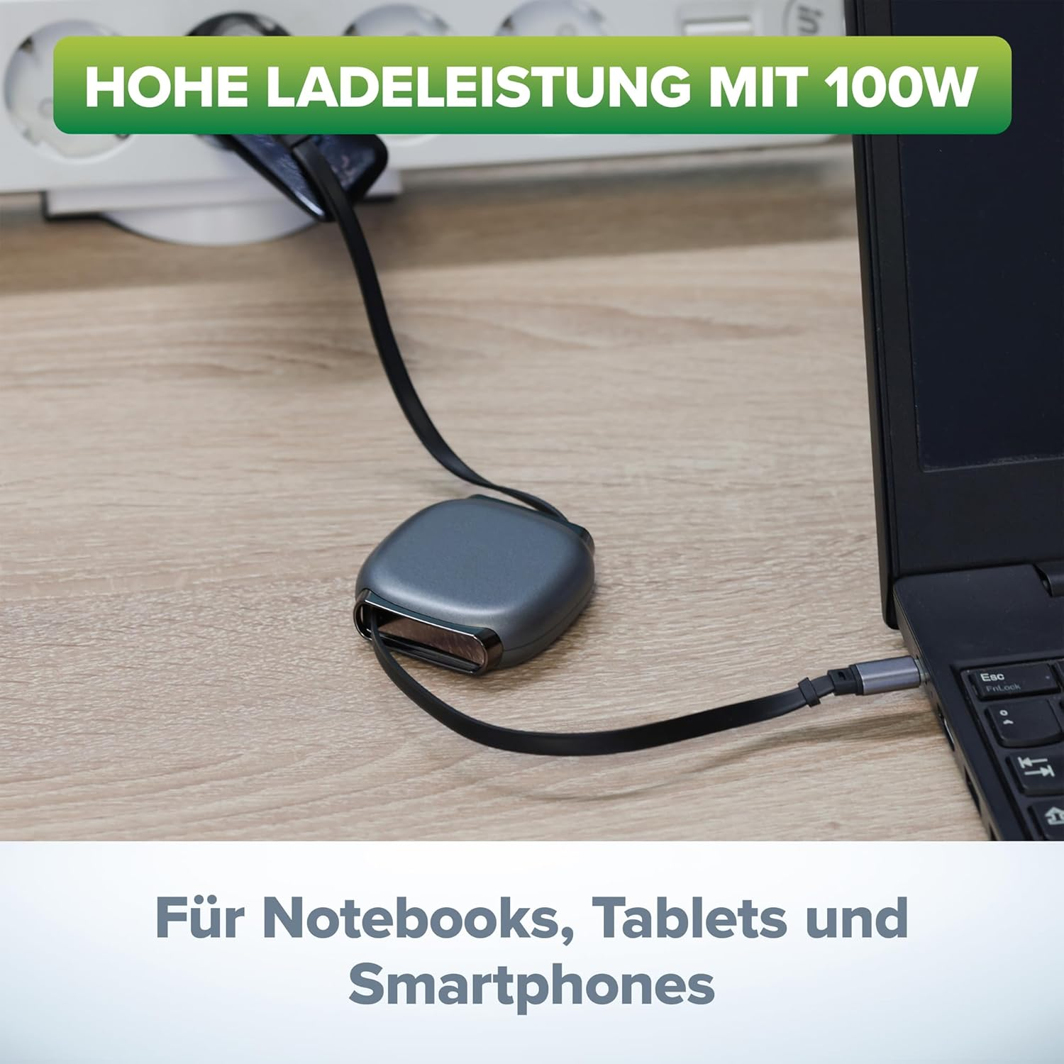 Ein schwarzes Ladekabel mit einem grauen Adapter ist an einem Laptop angeschlossen.