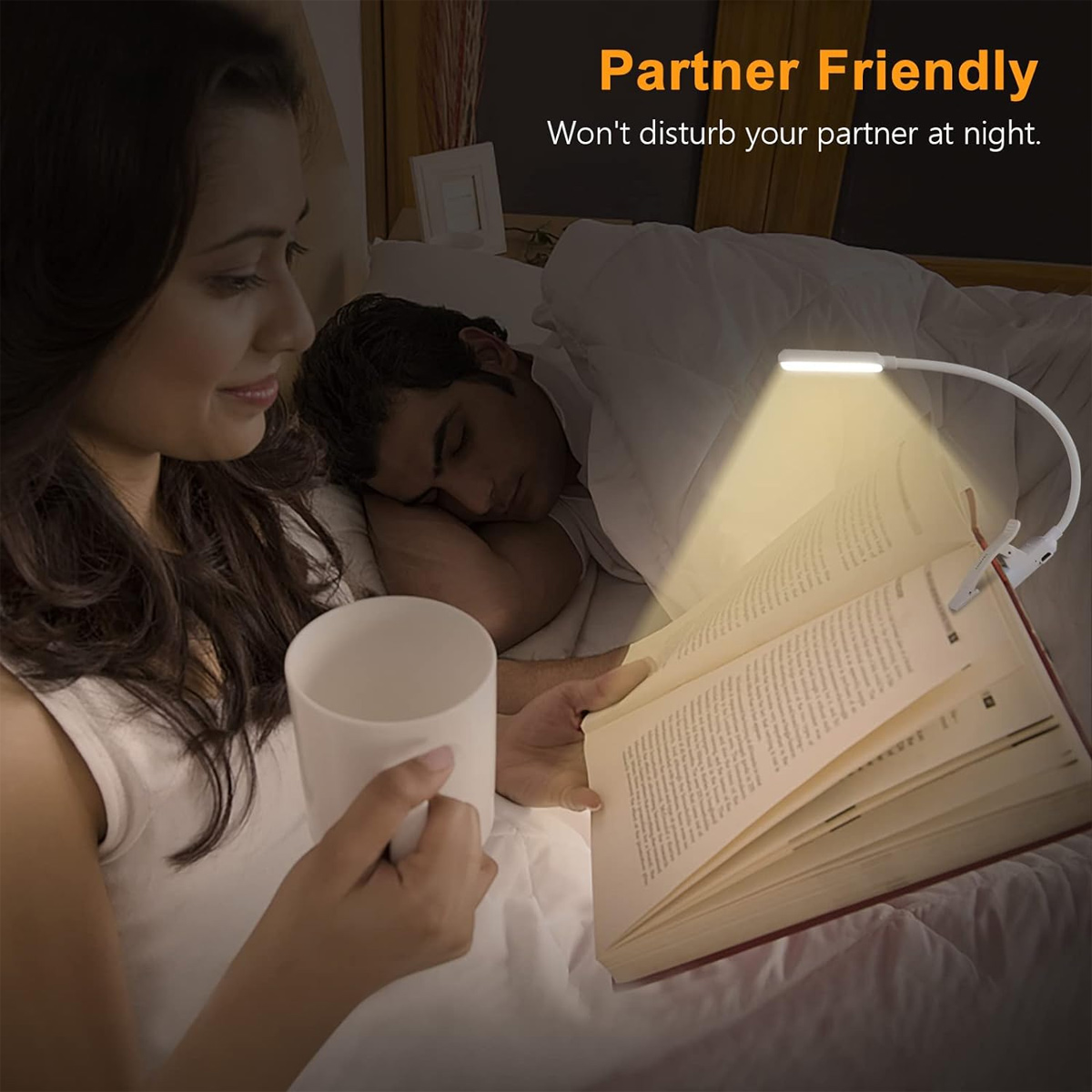 Eine Frau liest im Bett, während ihr Partner schläft. Eine Klemm-Leselampe beleuchtet das Buch.
