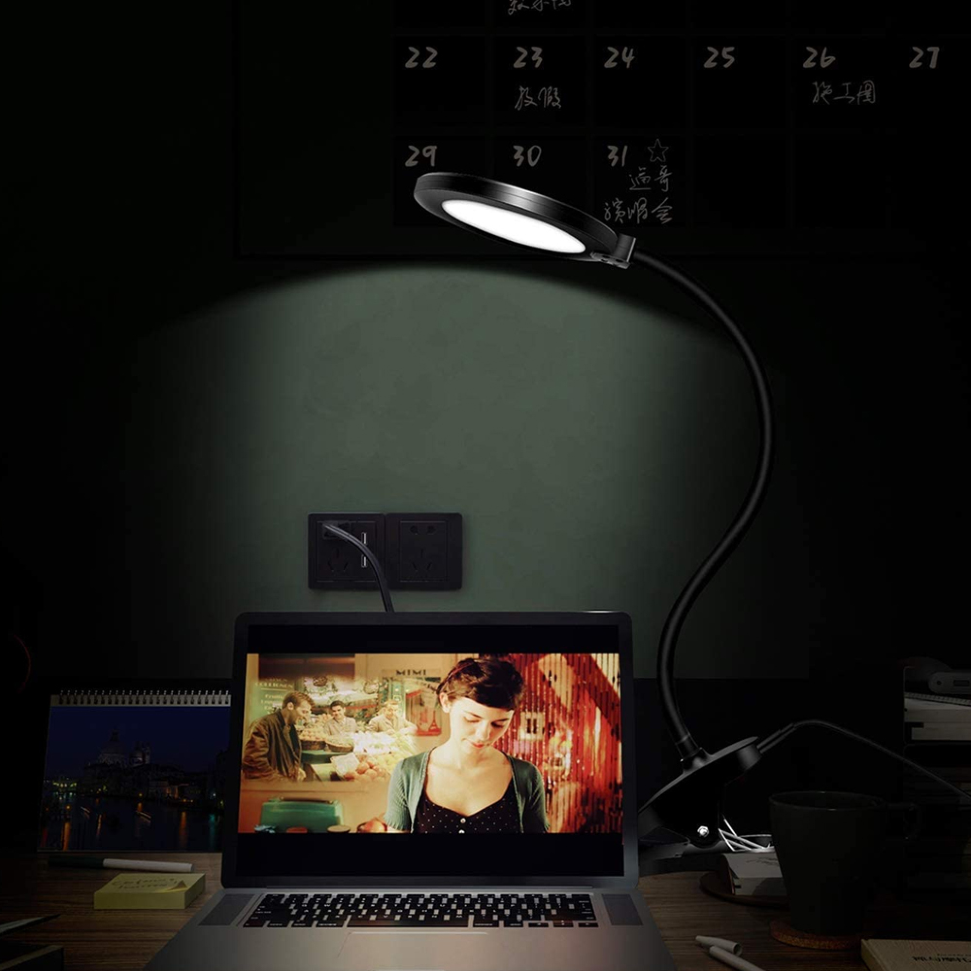 Ein Laptop mit einem Film und einer Lampe daneben auf einem Schreibtisch.