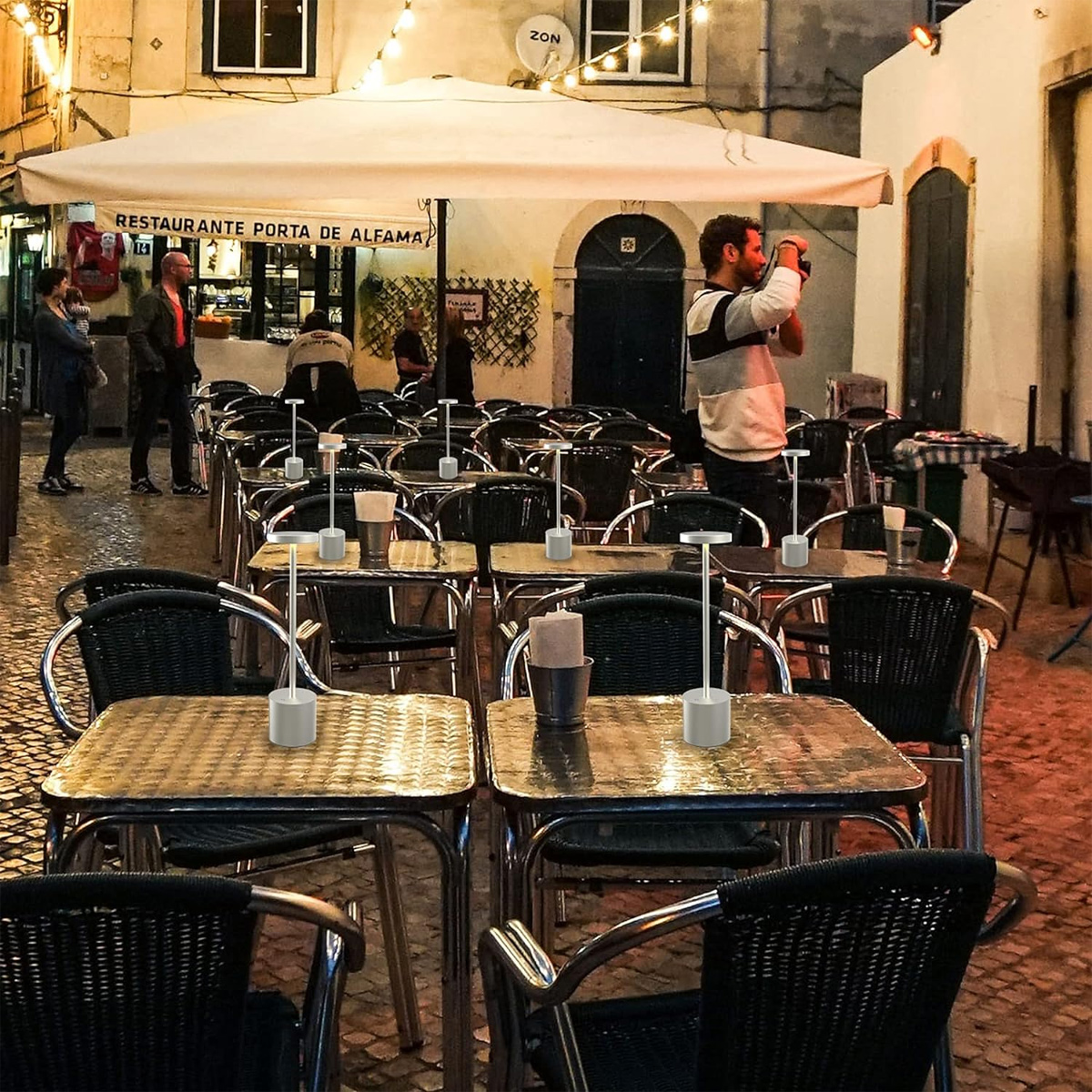 Auenbereich eines Restaurants mit gedeckten Tischen und Stöhlen, beleuchtet von Lichterketten.