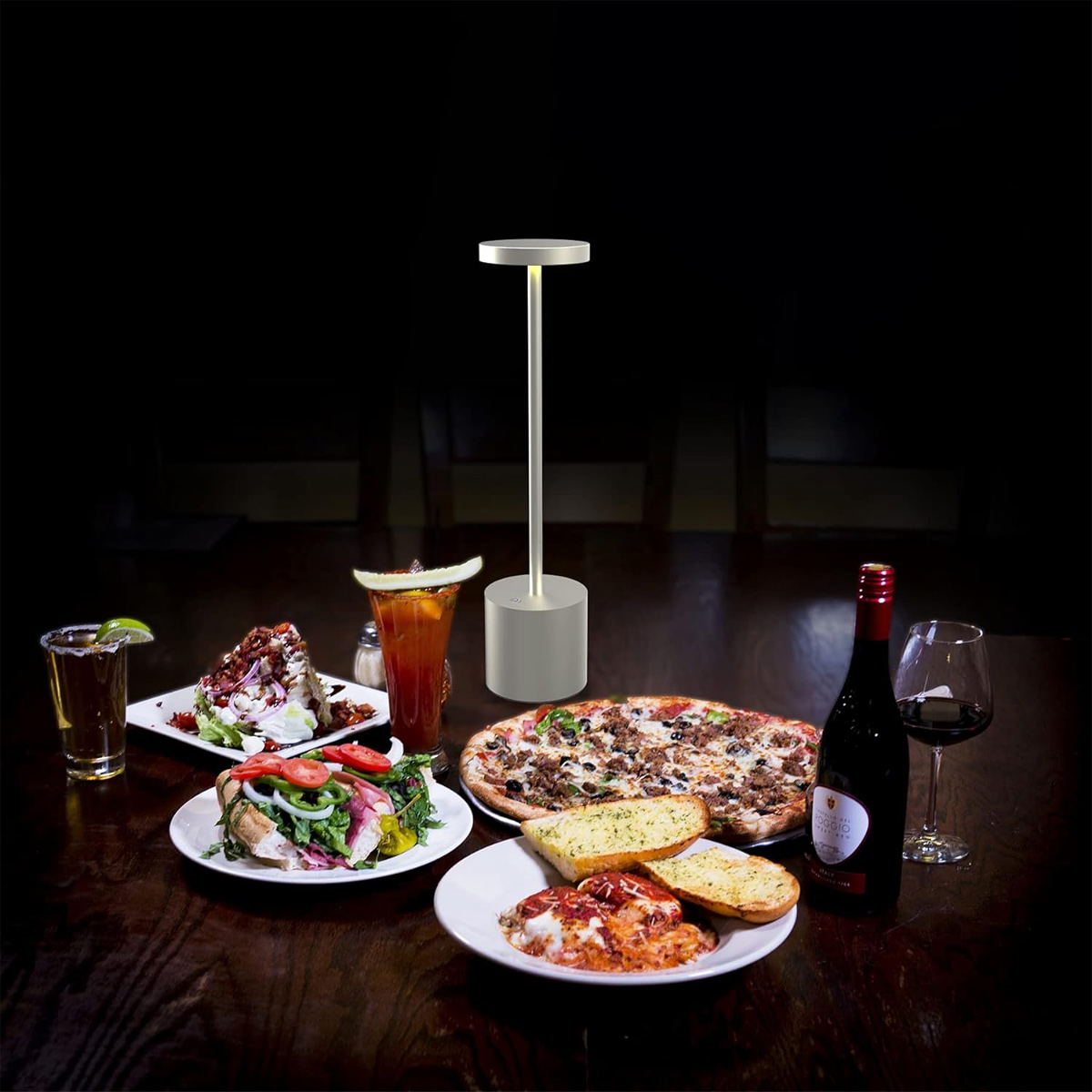 Ein Tisch mit Pizza, Salat, Lasagne, Getränken und einer Lampe.