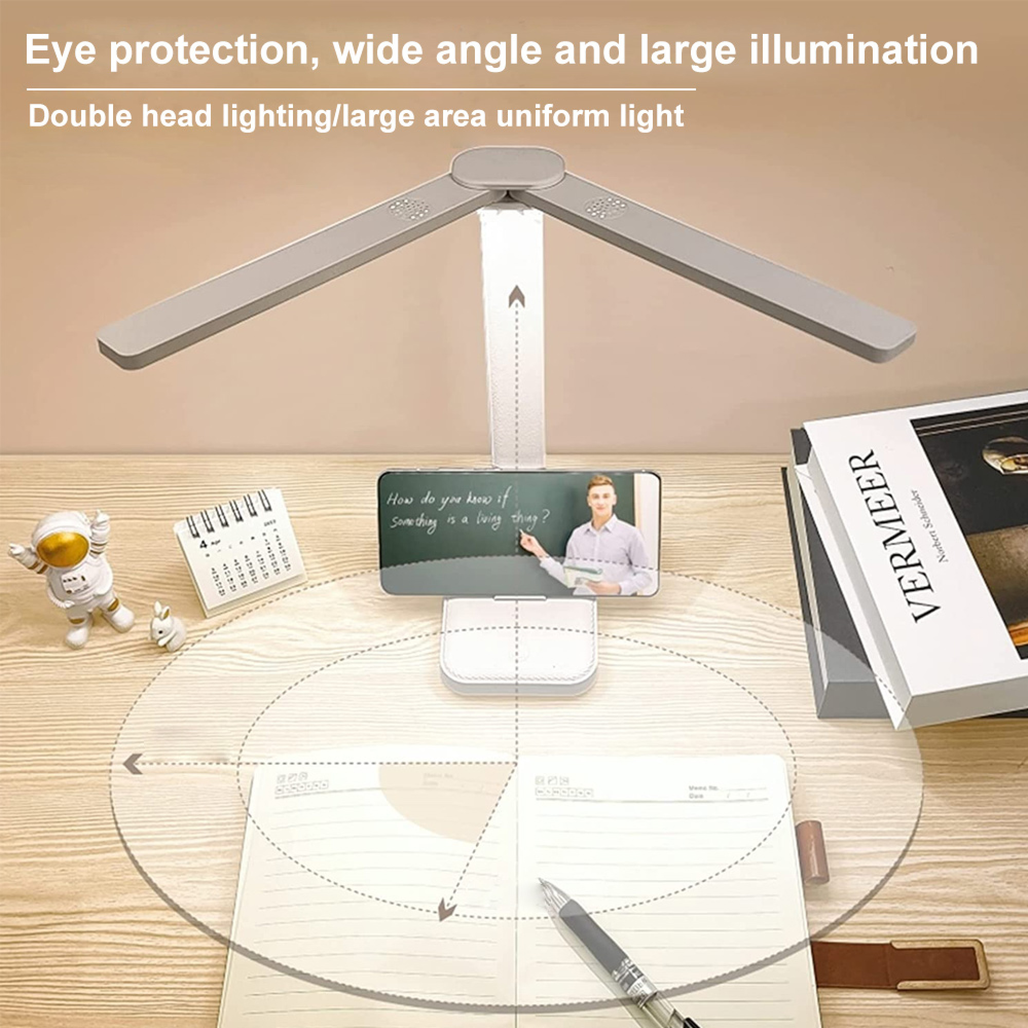 Ein Schreibtisch mit einer zweiköpfigen LED-Lampe, einem Telefon mit Lektion, Notizbuch und Büchern.