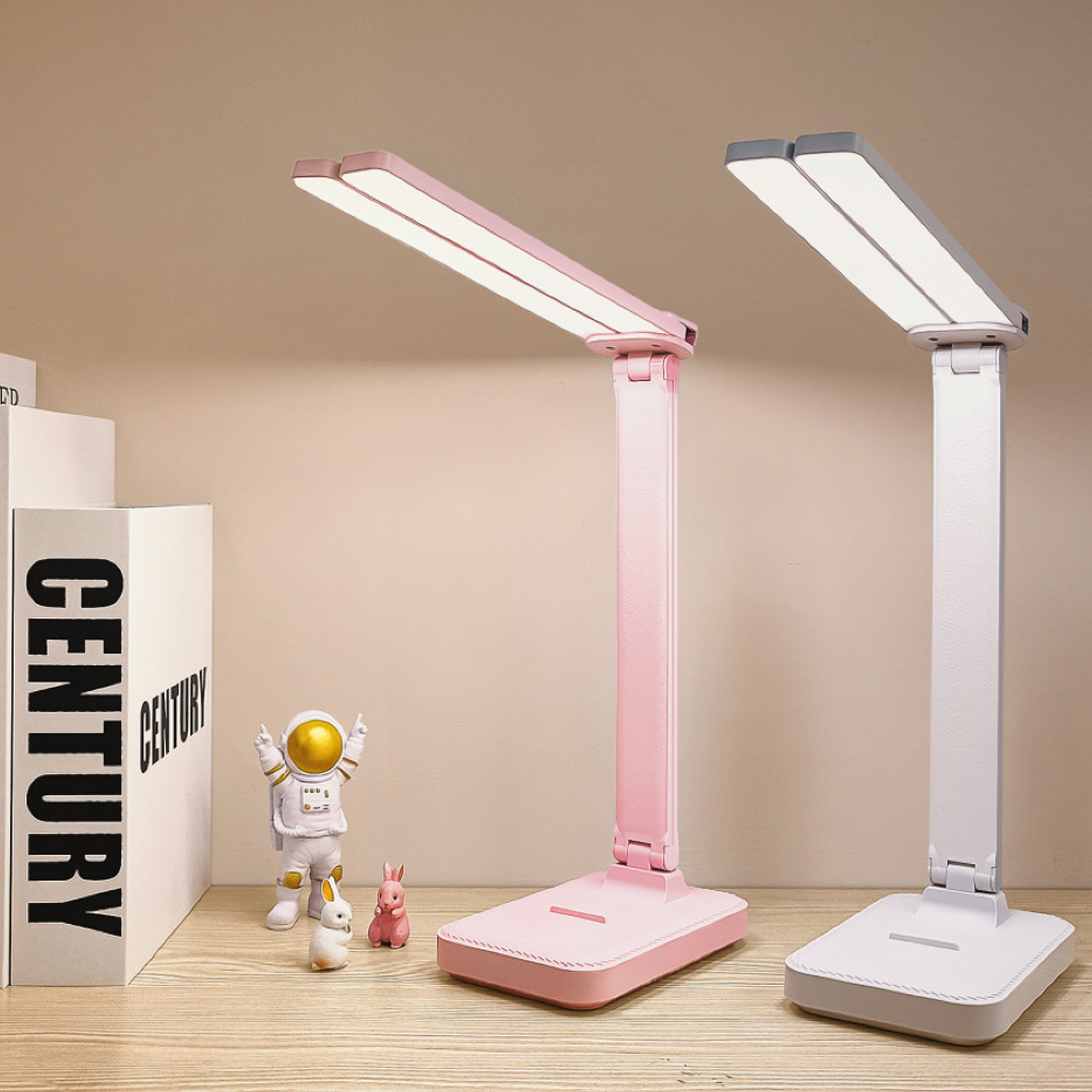 Zwei LED-Schreibtischlampen, eine pink und eine wei, stehen auf einem Holztisch neben Bchern.