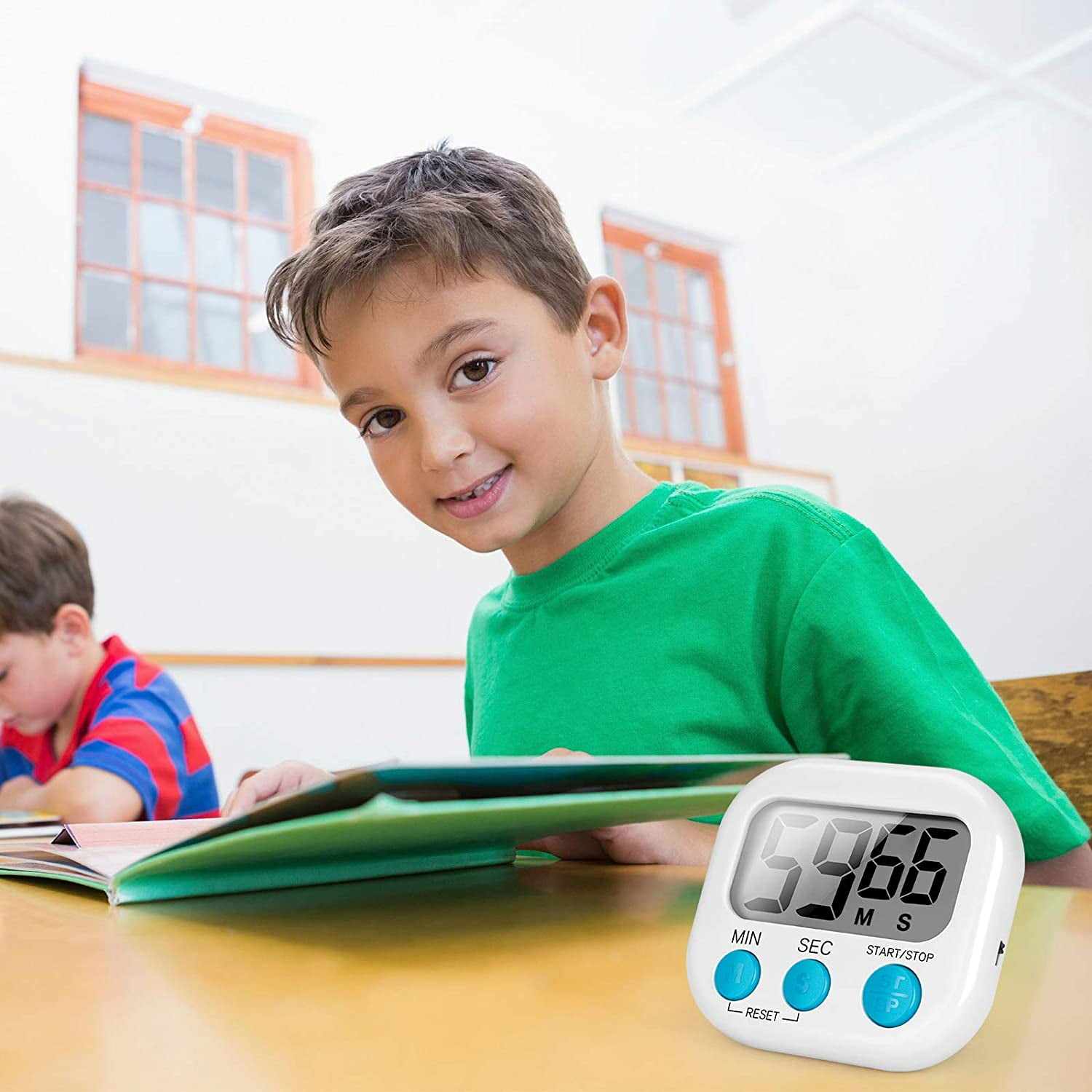 Ein Junge in einem grünen Hemd lächelt und schaut in die Kamera. Ein digitaler Timer steht auf einem Tisch.