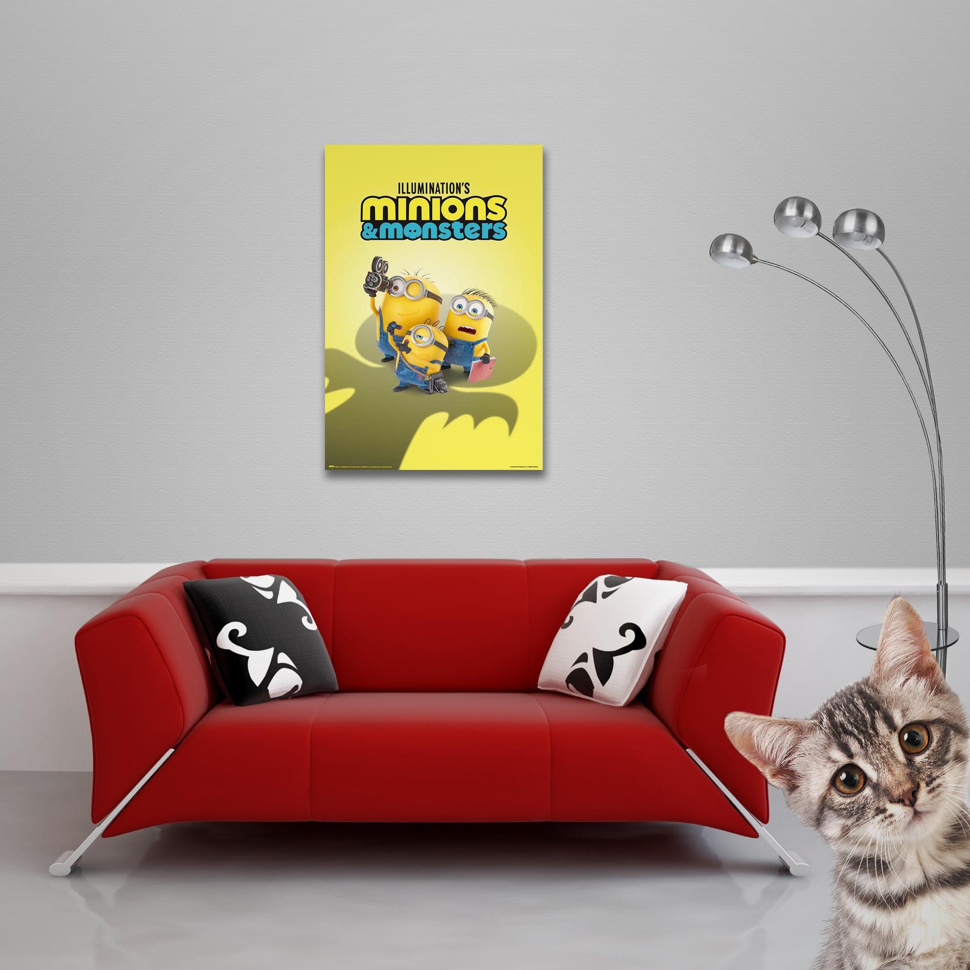 Minions-Poster über einem roten Sofa. Ein Kätzchen lugt von rechts.