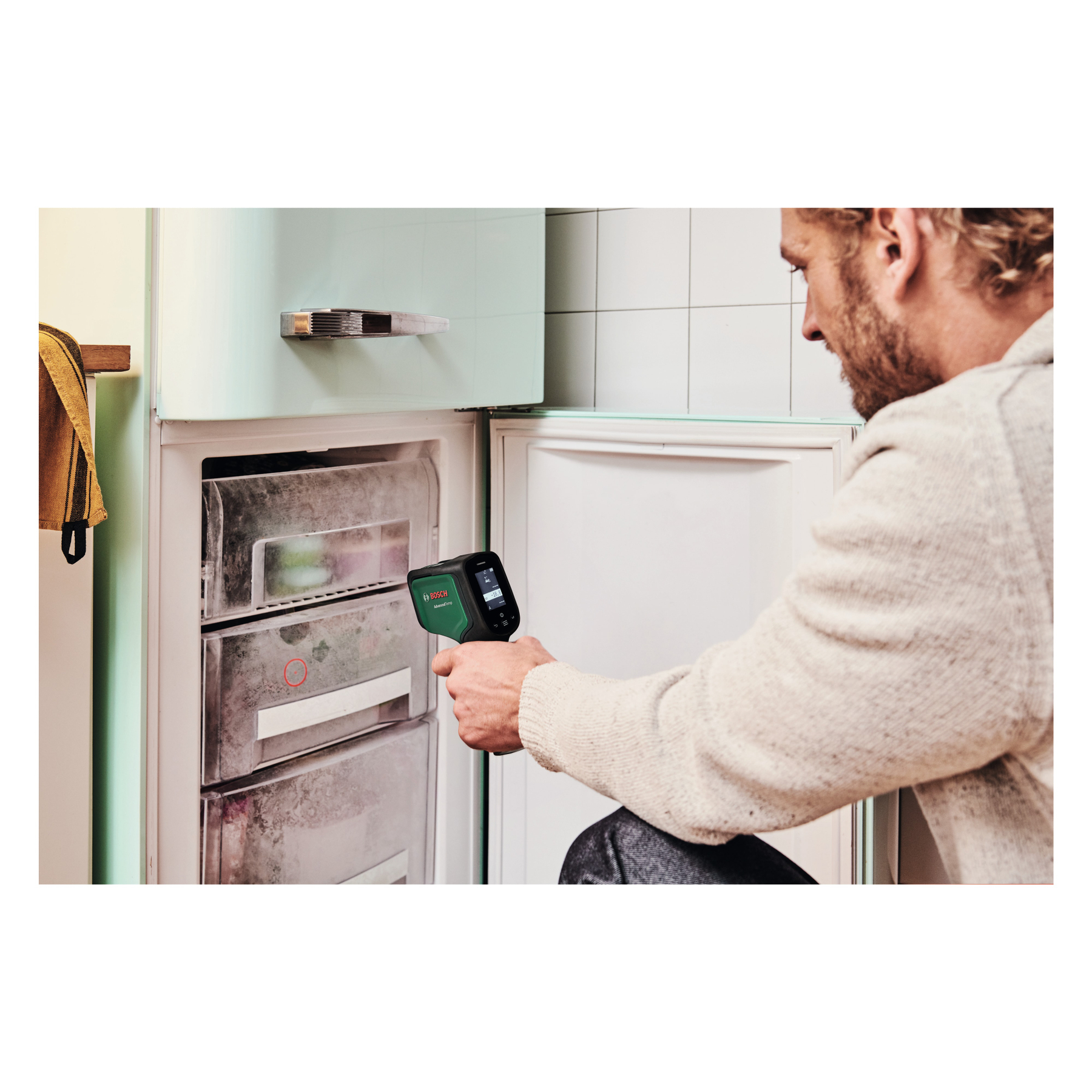 Mann misst mit Bosch-Thermometer die Temperatur im Gefrierschrank.