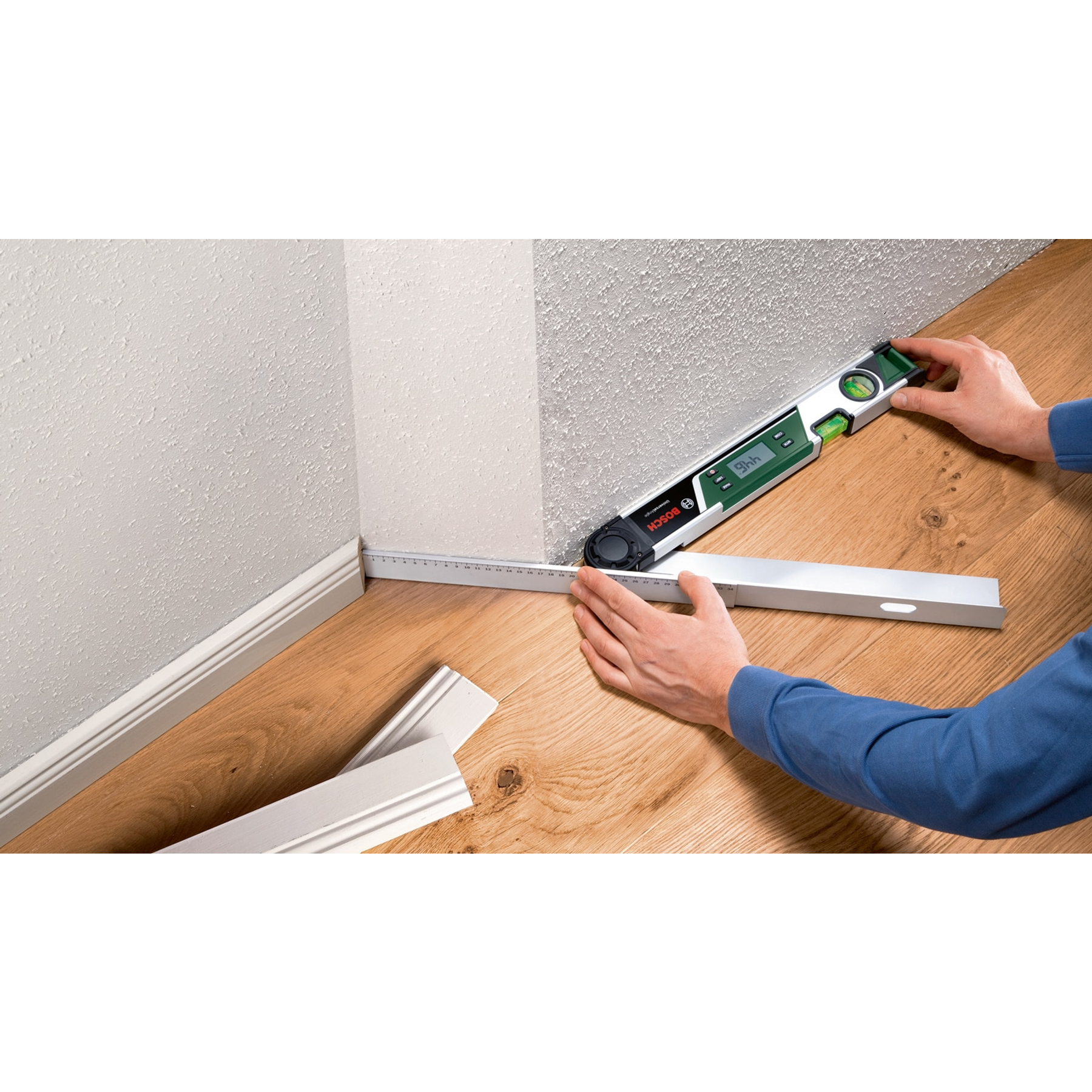 Eine Person misst mit einem digitalen Winkelmesser und Lineal in einer Ecke.