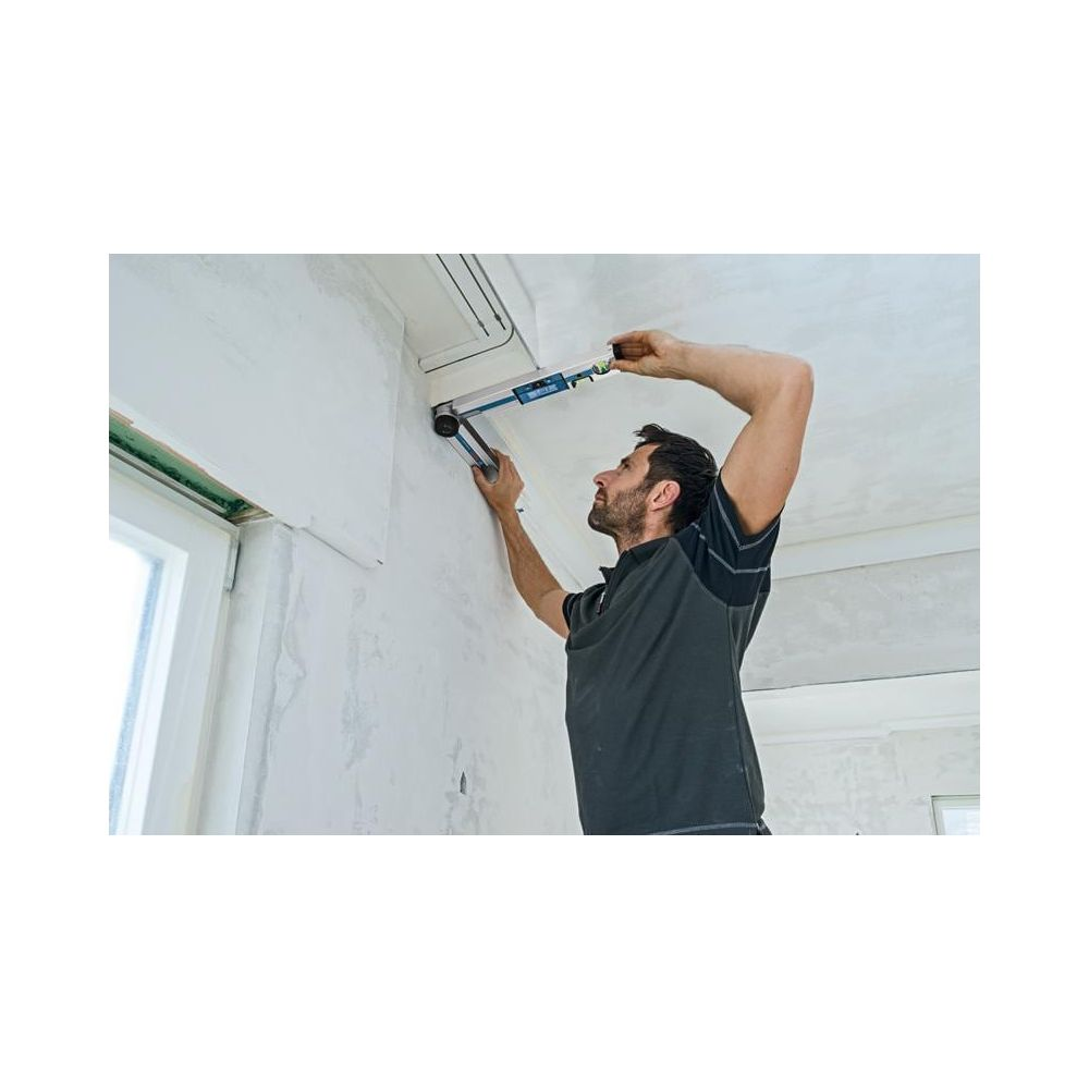 Mann benutzt ein Winkelmessgerät an einer Wand in der Nähe eines Fensters.