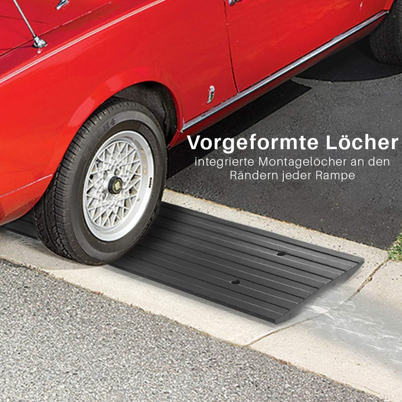 Ein rotes Auto fährt über eine schwarze Rampe, die auf dem Bürgersteig liegt.