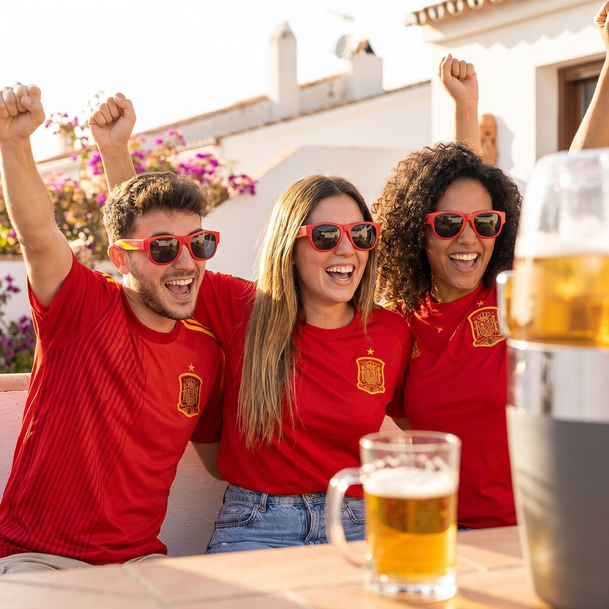 Tre tifosi che esultano in maglia rossa e occhiali da sole con birra.