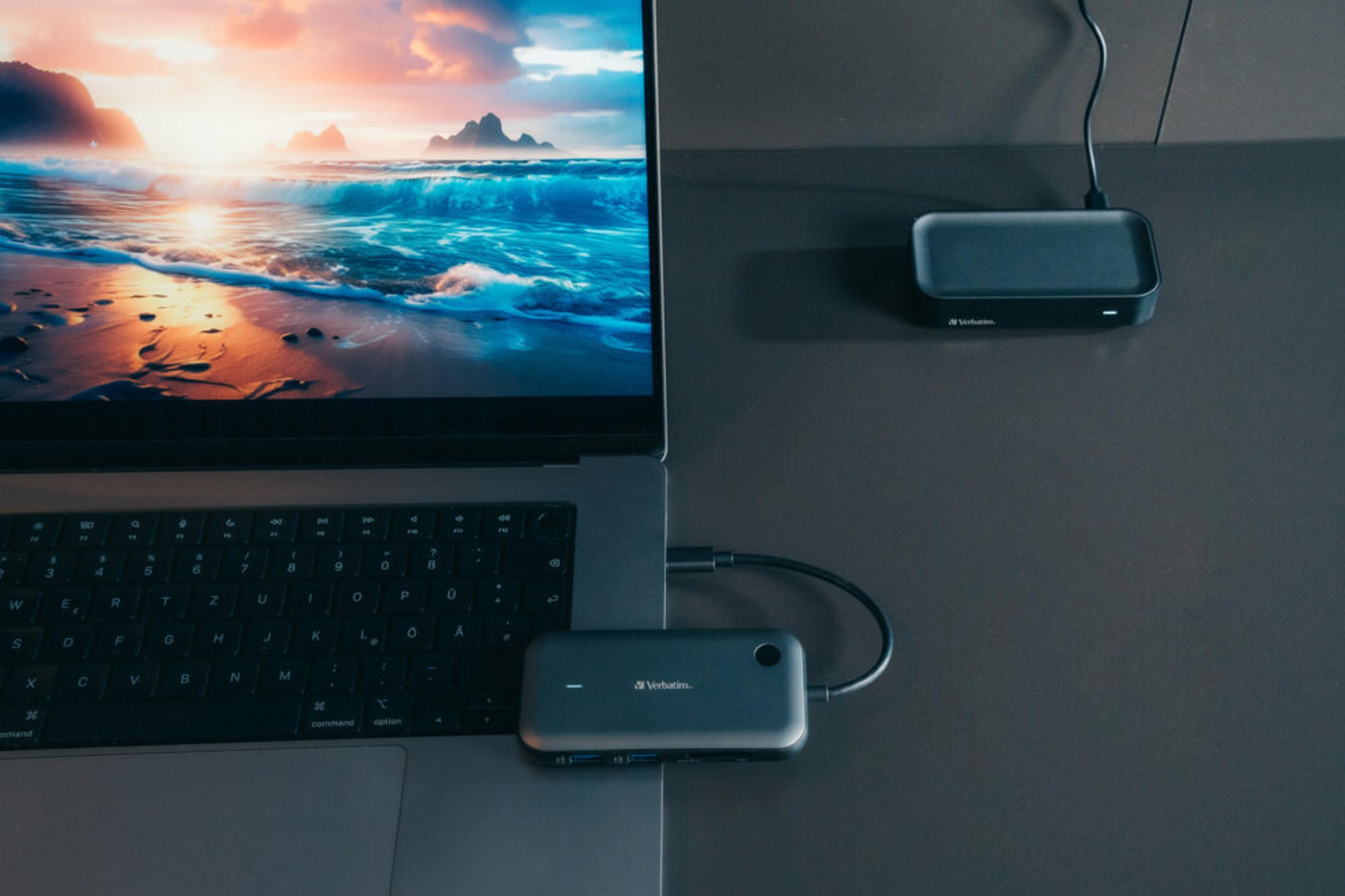 Un laptop mostra una scena di tramonto sulla spiaggia. Un hub è collegato.