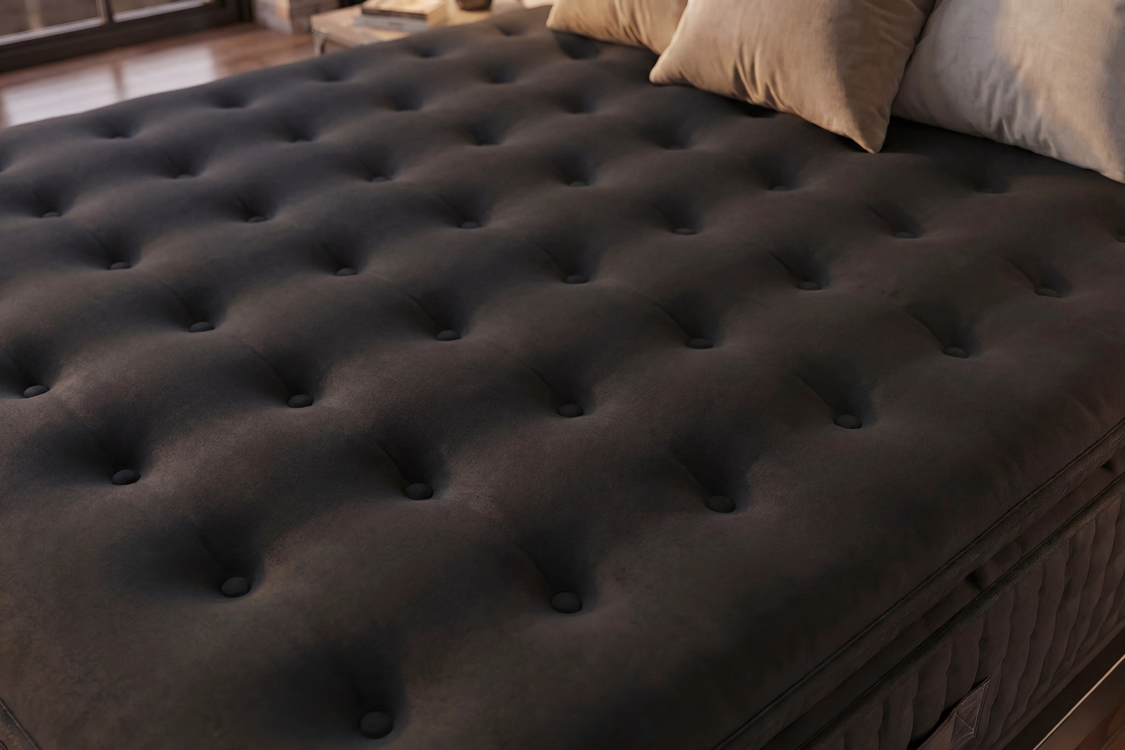 Un colchón gris oscuro con mechones y dos almohadas beige claro encima.