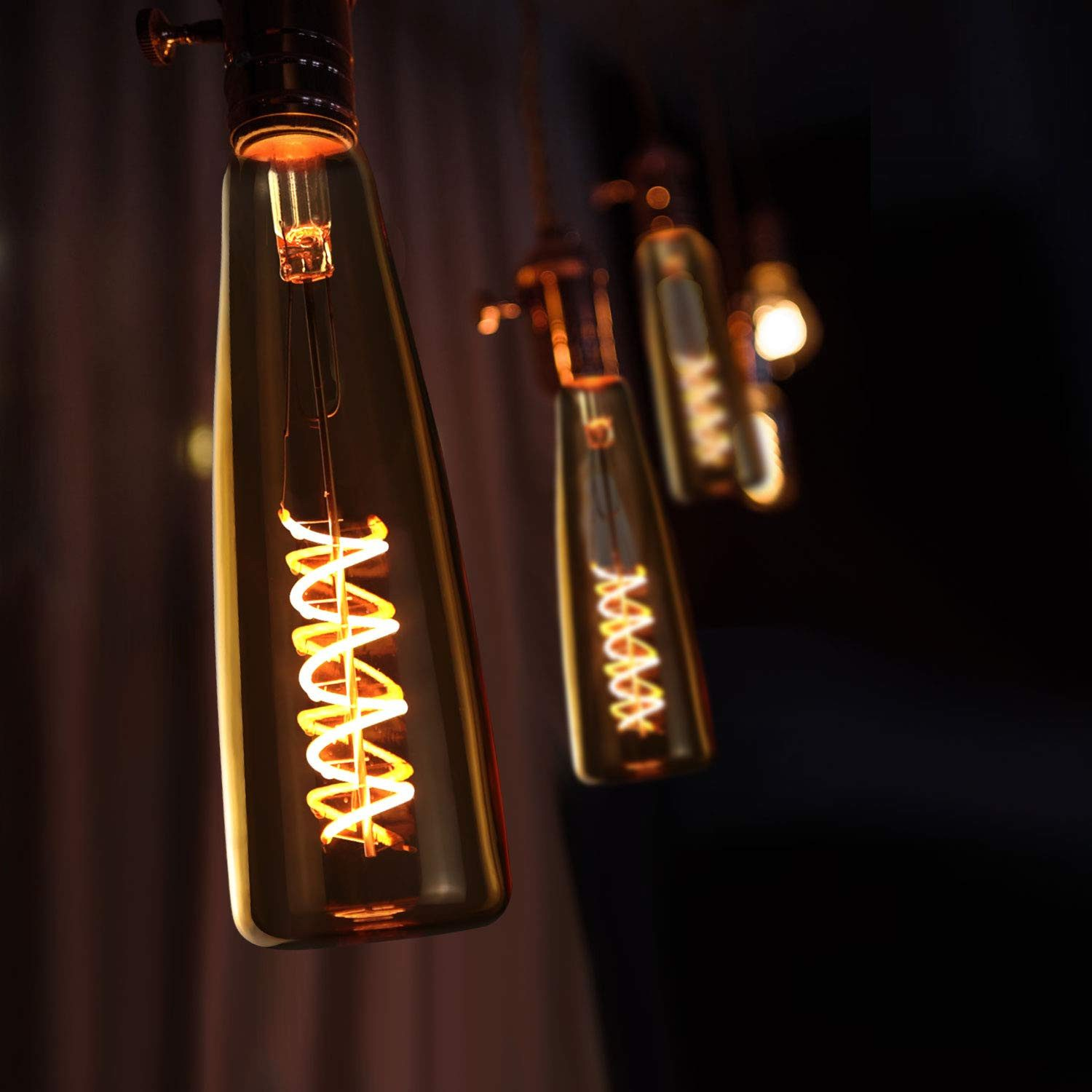 Nahaufnahme von Vintage-Edison-Glühbirnen mit glühenden Spiralfilamenten vor dunklem Hintergrund.