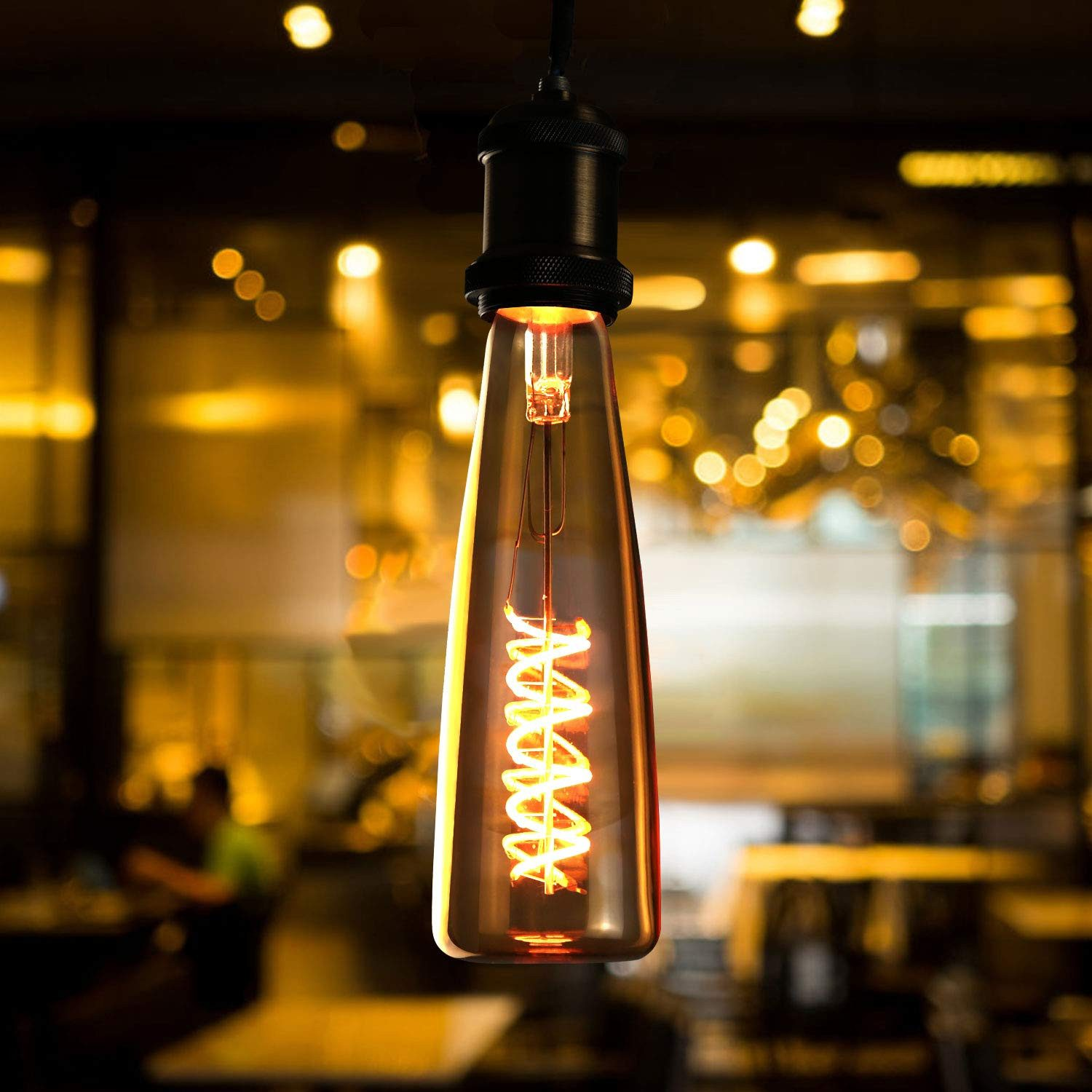 Eine Edison-Glühbirne hängt im Vordergrund, beleuchtet einen dunklen Raum.