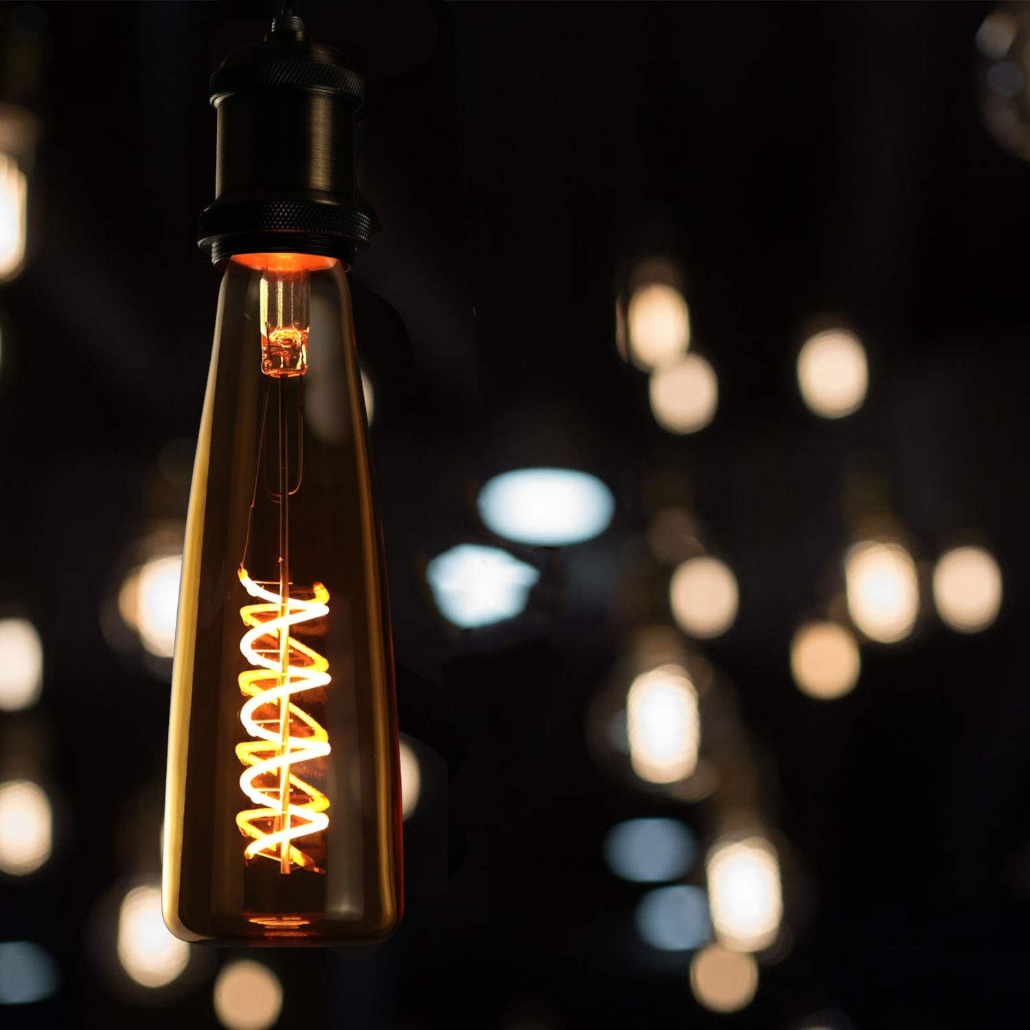 Eine bernsteinfarbene Edison-Glühbirne mit Spiralwendel leuchtet im Dunkeln.