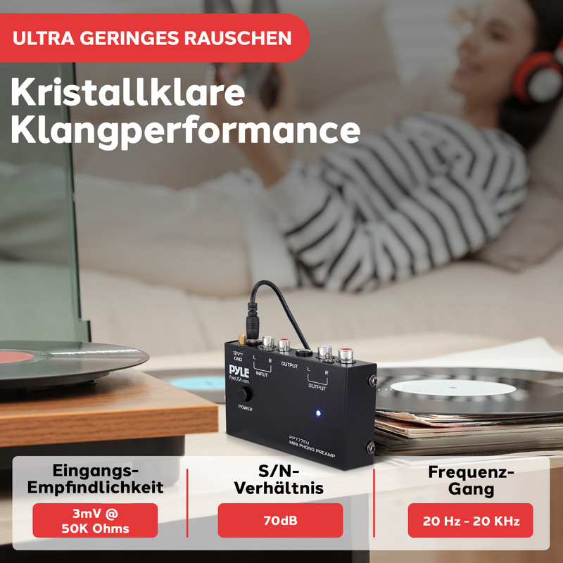 Schwarzer Mini-Phono-Vorverstärker mit Anschlüssen, daneben Schallplatten und Plattenspieler.