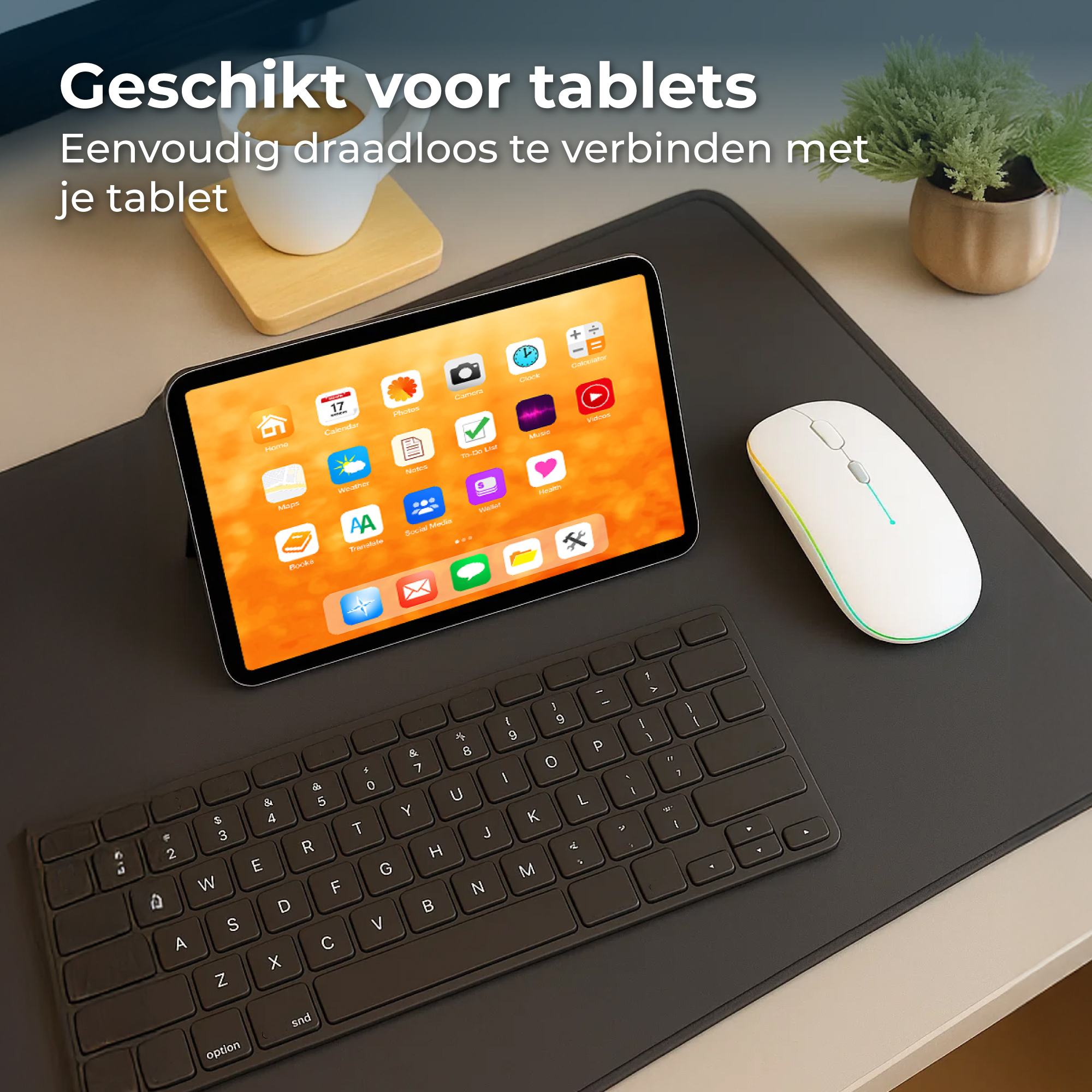 Een tablet, toetsenbord, muis en plant op een bureau.