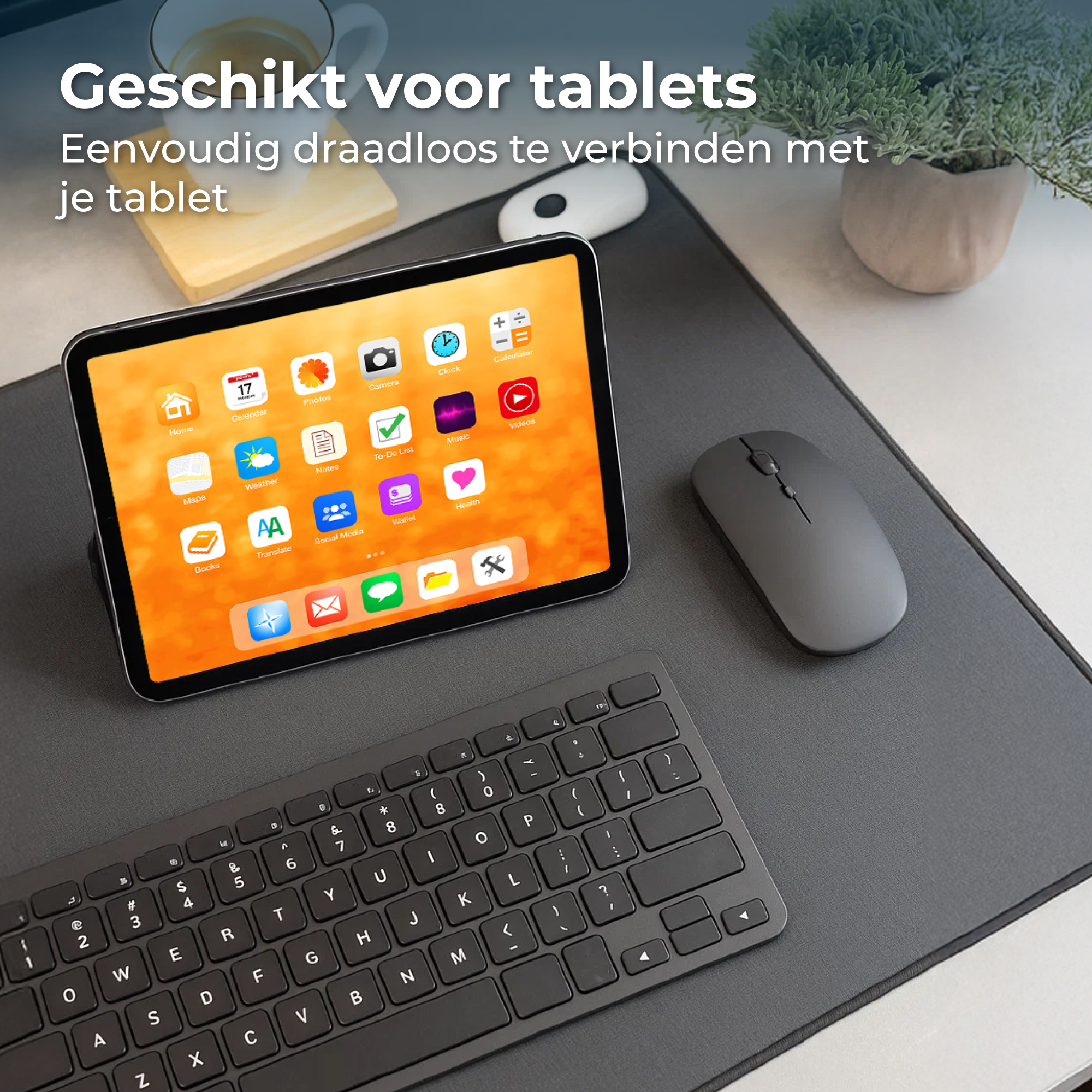 Een tablet met toetsenbord, muis en kop koffie op een bureauonderlegger.