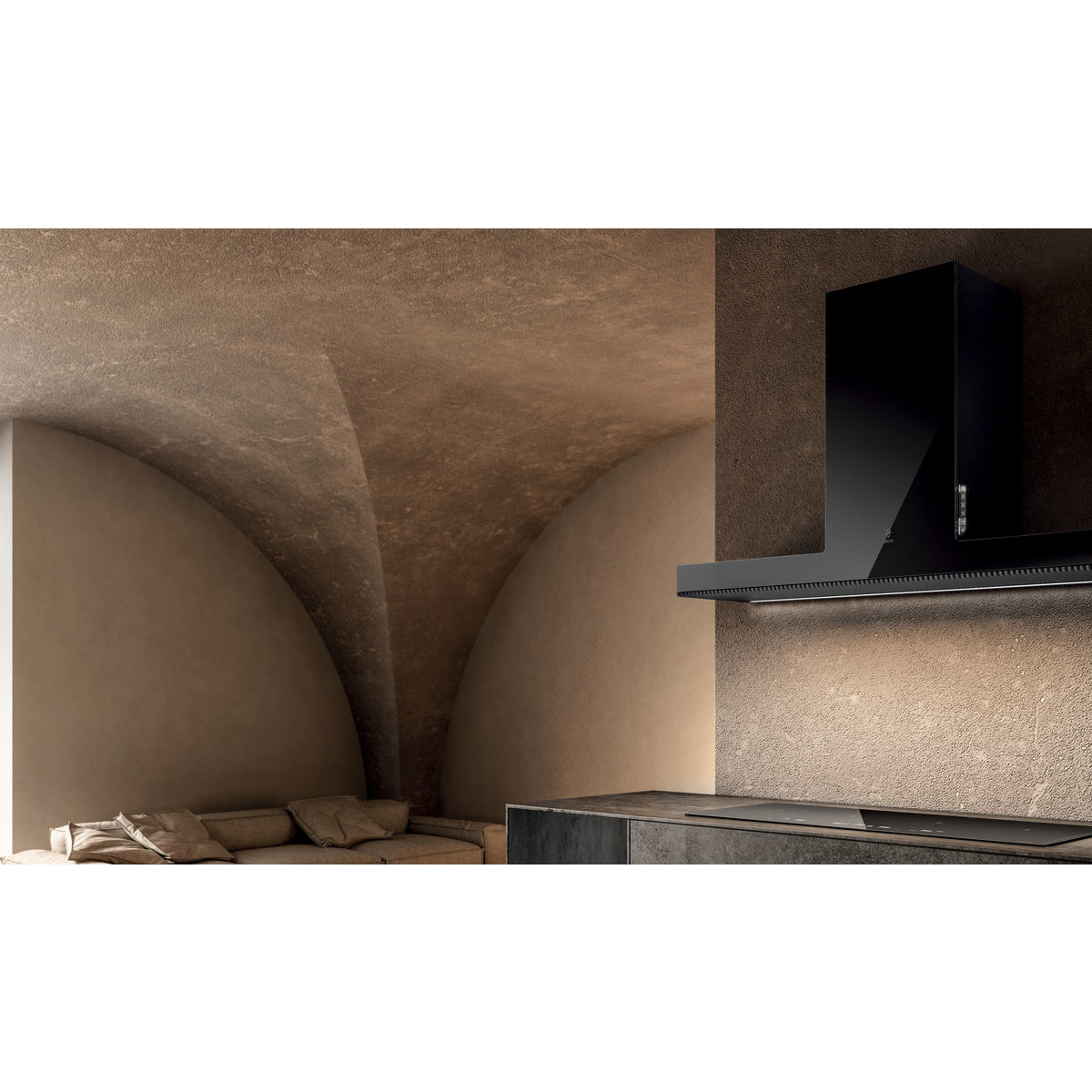 Cappa aspirante nera sopra un piano cottura a induzione in una cucina moderna con divano.