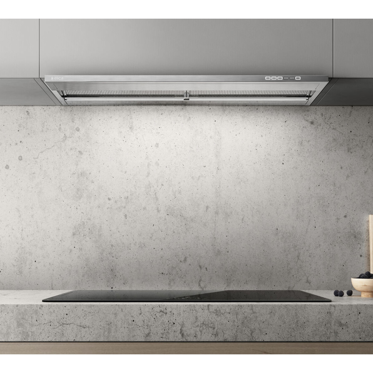 Cucina moderna con cappa, piano cottura e parete in cemento.