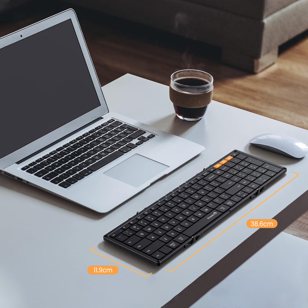 Portátil, teclado y ratón sobre un escritorio, con una taza de café.