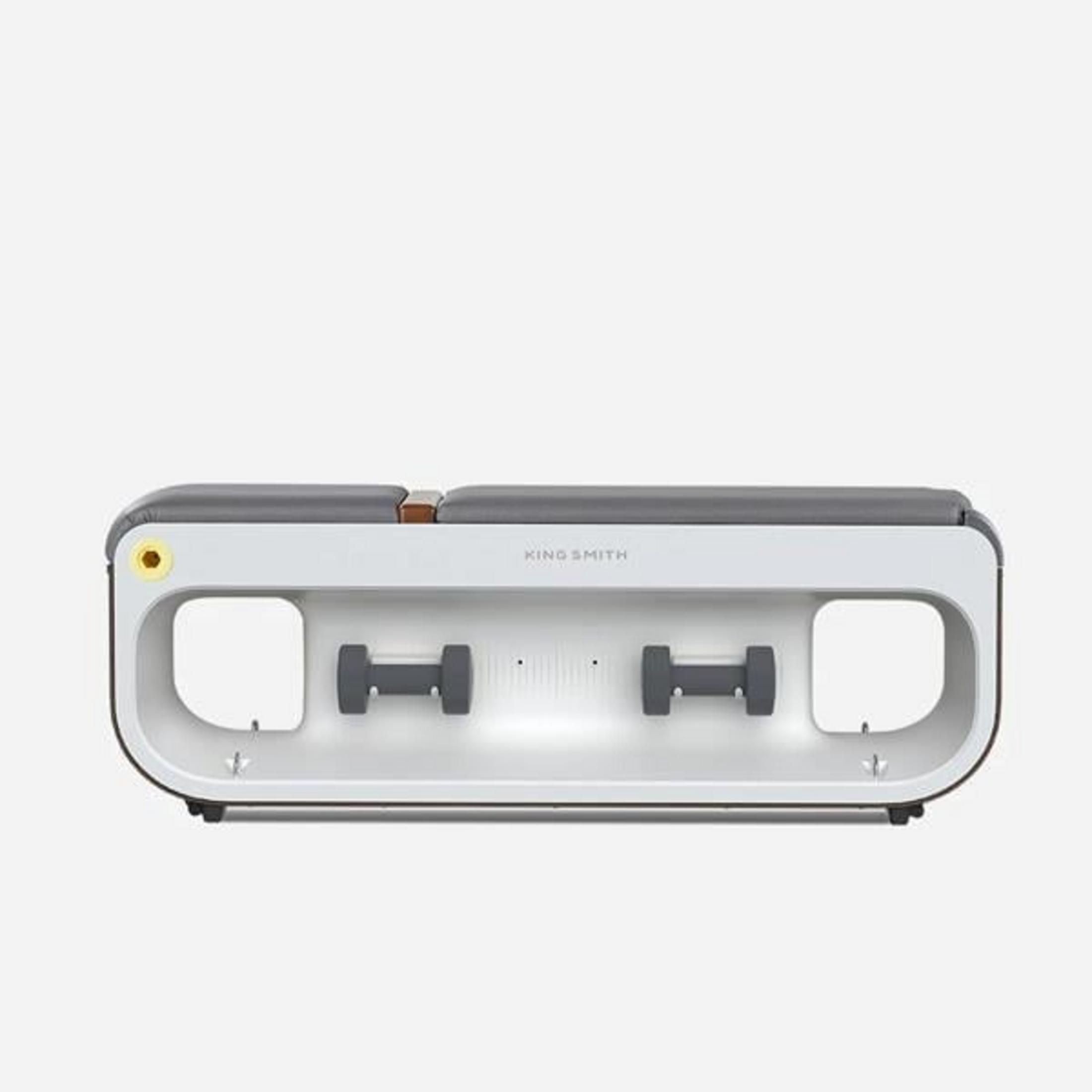 A gray fitness machine with two dumbbells, a yellow button, and wood accents.