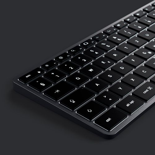 Nahaufnahme einer schwarzen Tastatur mit beleuchteten Tasten auf dunklem Hintergrund.