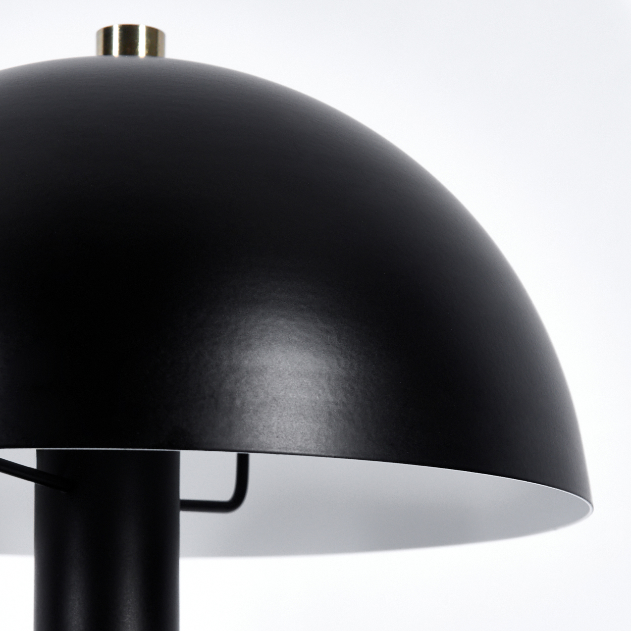 Nahaufnahme einer schwarzen Lampe mit einem goldenen Akzent oben.