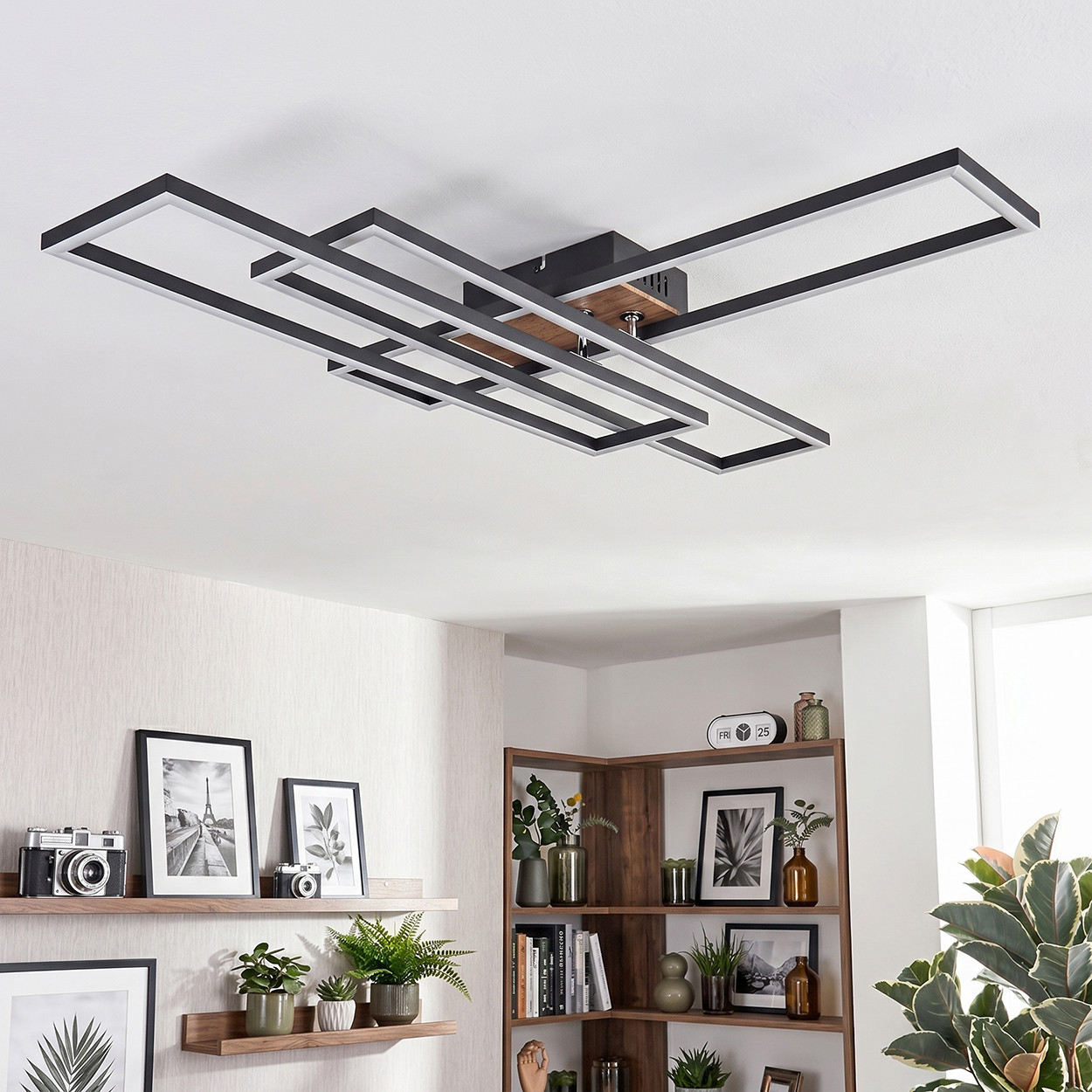 Eine moderne Deckenleuchte mit rechteckigen Rahmen in Schwarz und Weiß, über einem Regal mit Deko.