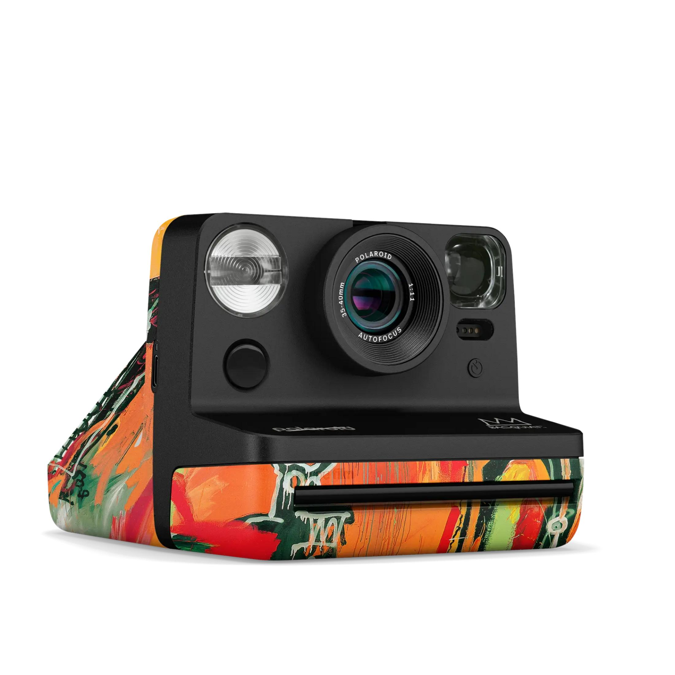 Aparat Polaroid z kolorowym, abstrakcyjnym wzorem artystycznym w odcieniach pomarańczu, zieleni i czerwieni.