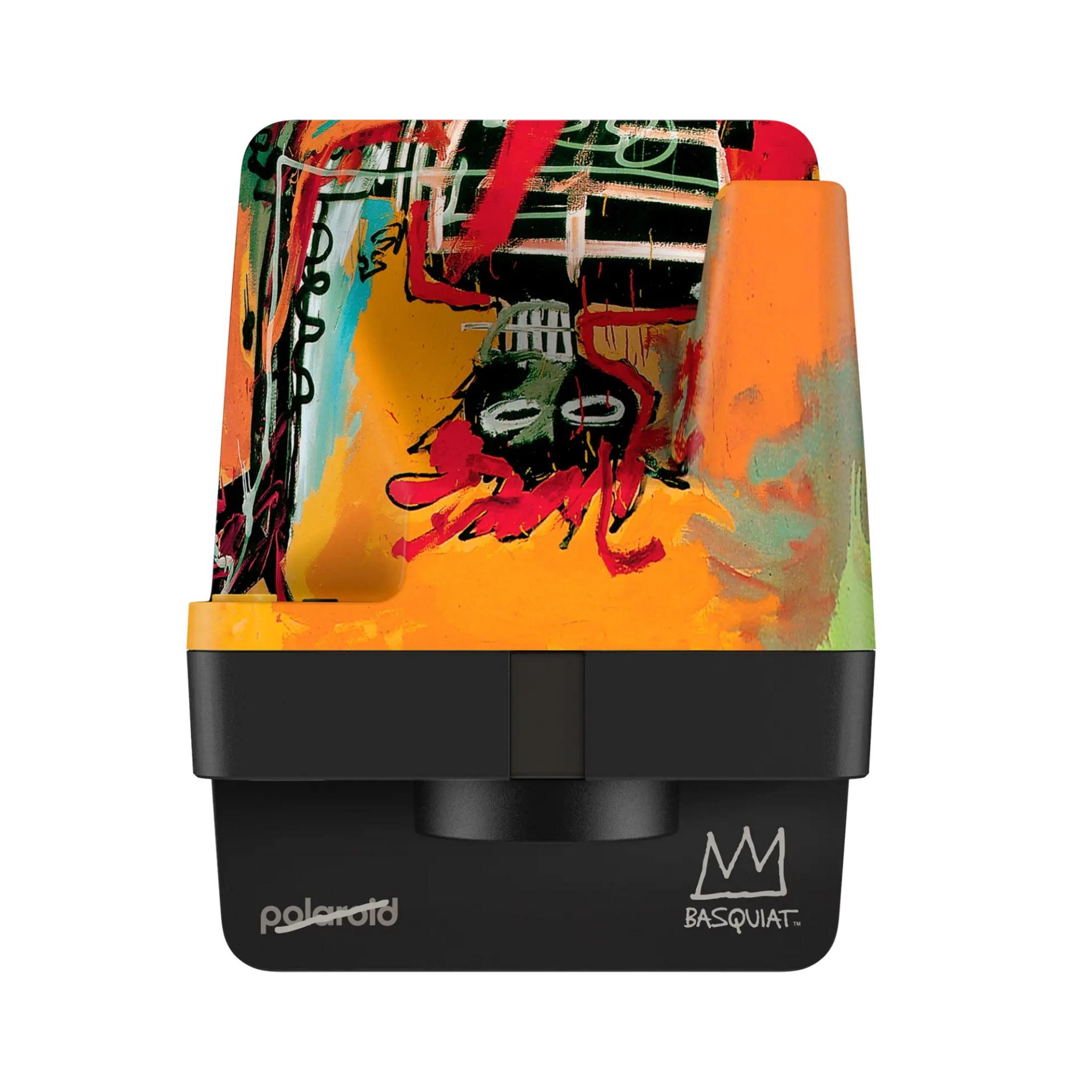 Aparat Polaroid ozdobiony grafiką Basquiata w kolorach żółtym, pomarańczowym, czerwonym, zielonym i czarnym.