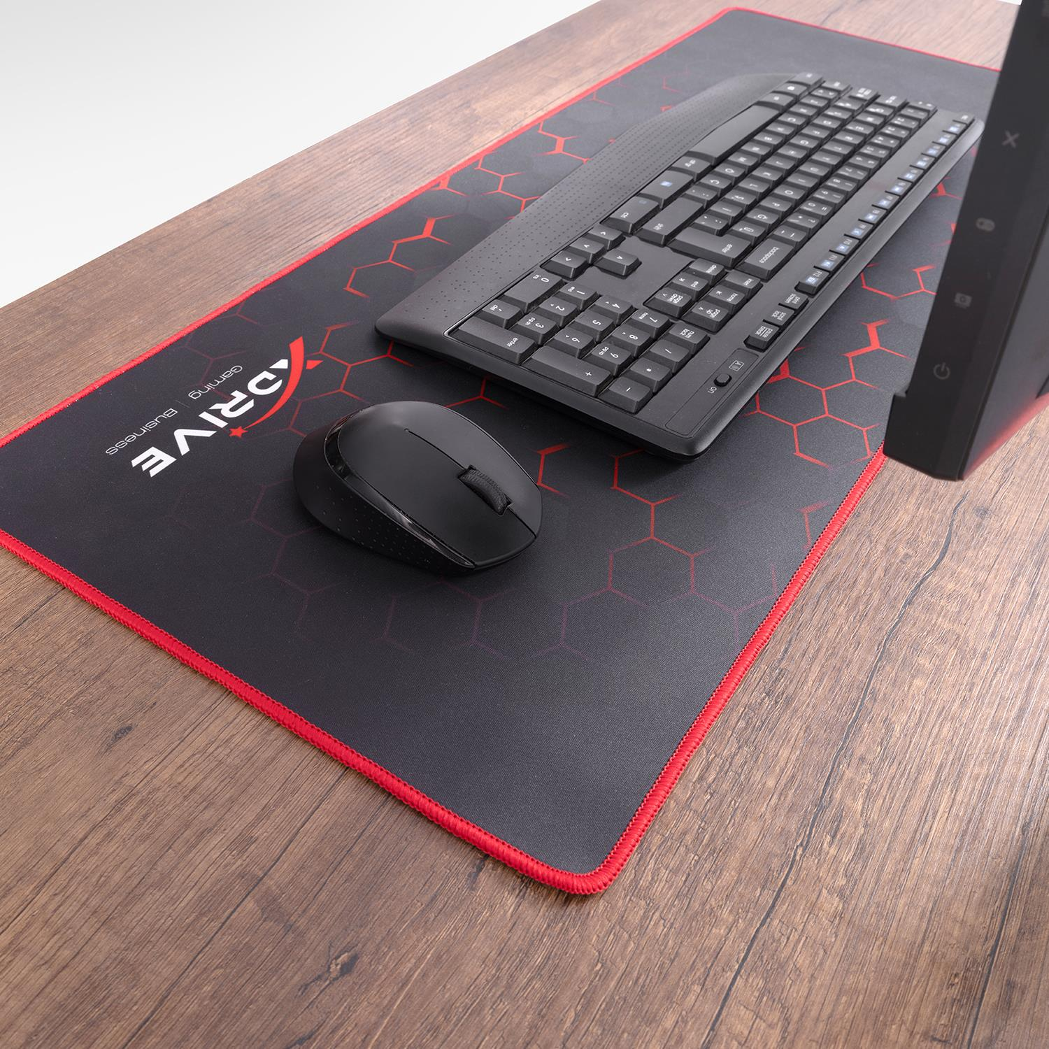 Kırmızı altıgenli siyah mousepad üzerinde siyah klavye ve fare. Ahşap masa.