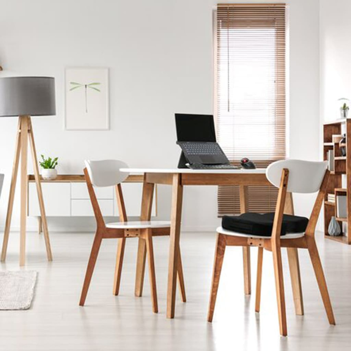 Modernes Büro mit Holztisch, Stühlen, Laptop und Stehlampe.