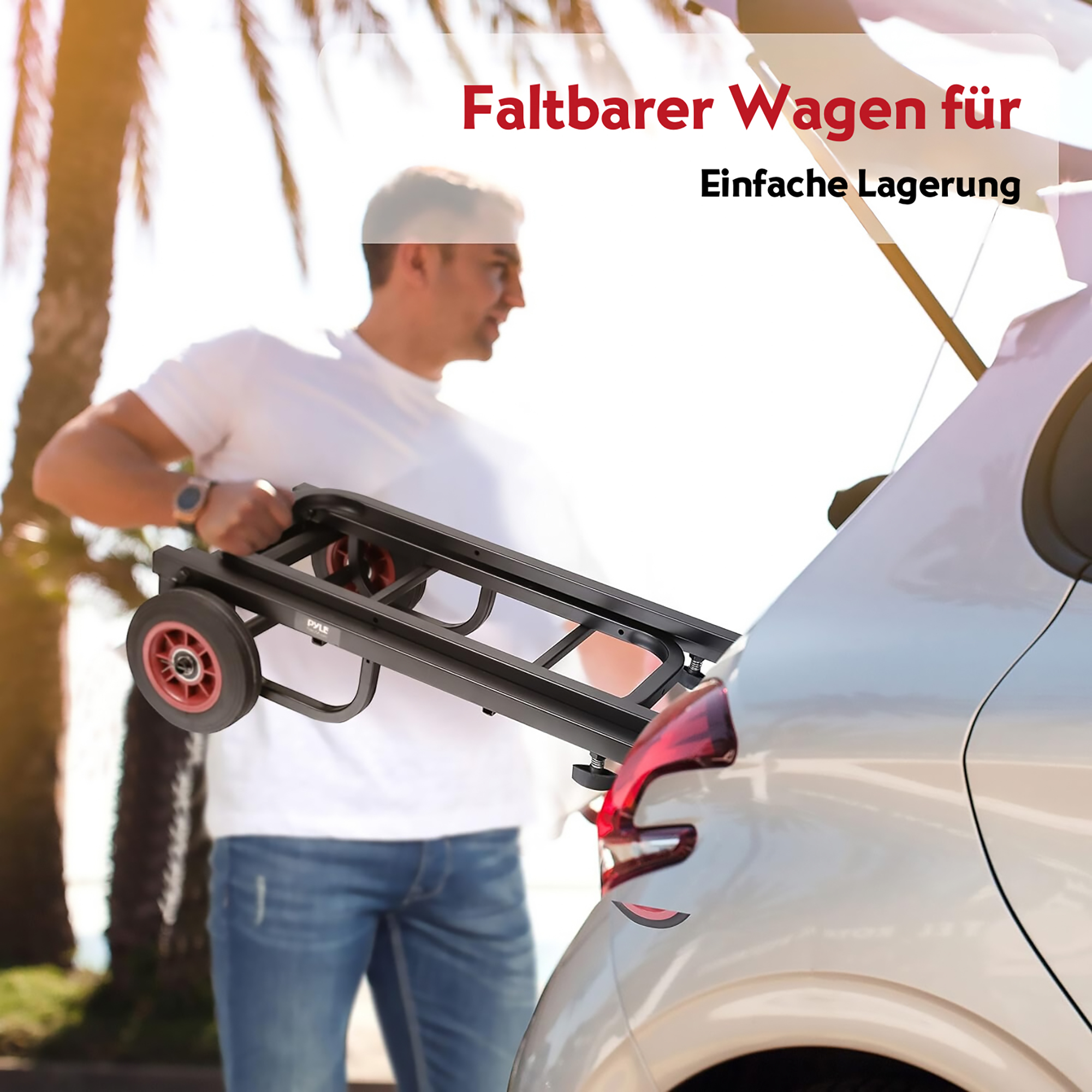 Mann verstaut einen schwarzen Faltwagen mit roten Rädern im Kofferraum eines Autos.