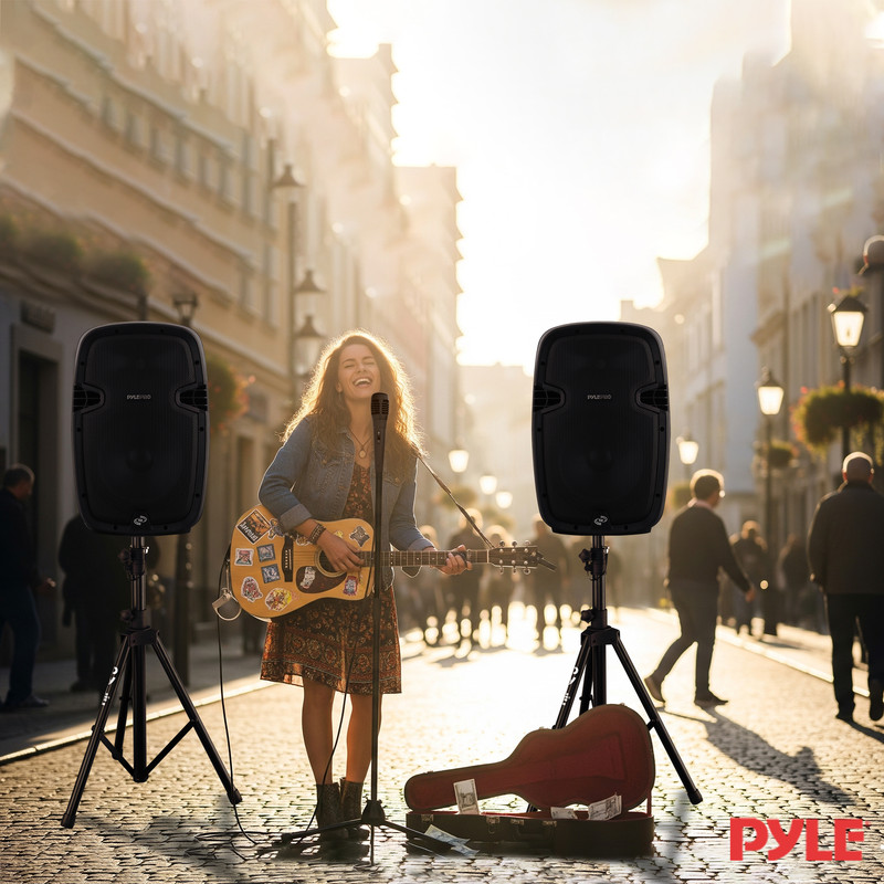 Frau spielt Gitarre und singt auf einer Straße mit zwei Lautsprechern und einem Mikrofon.