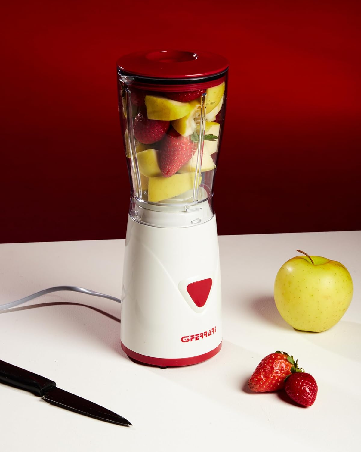 Elma ve çilek dolu blender, yanında bir elma, çilek ve bıçak.