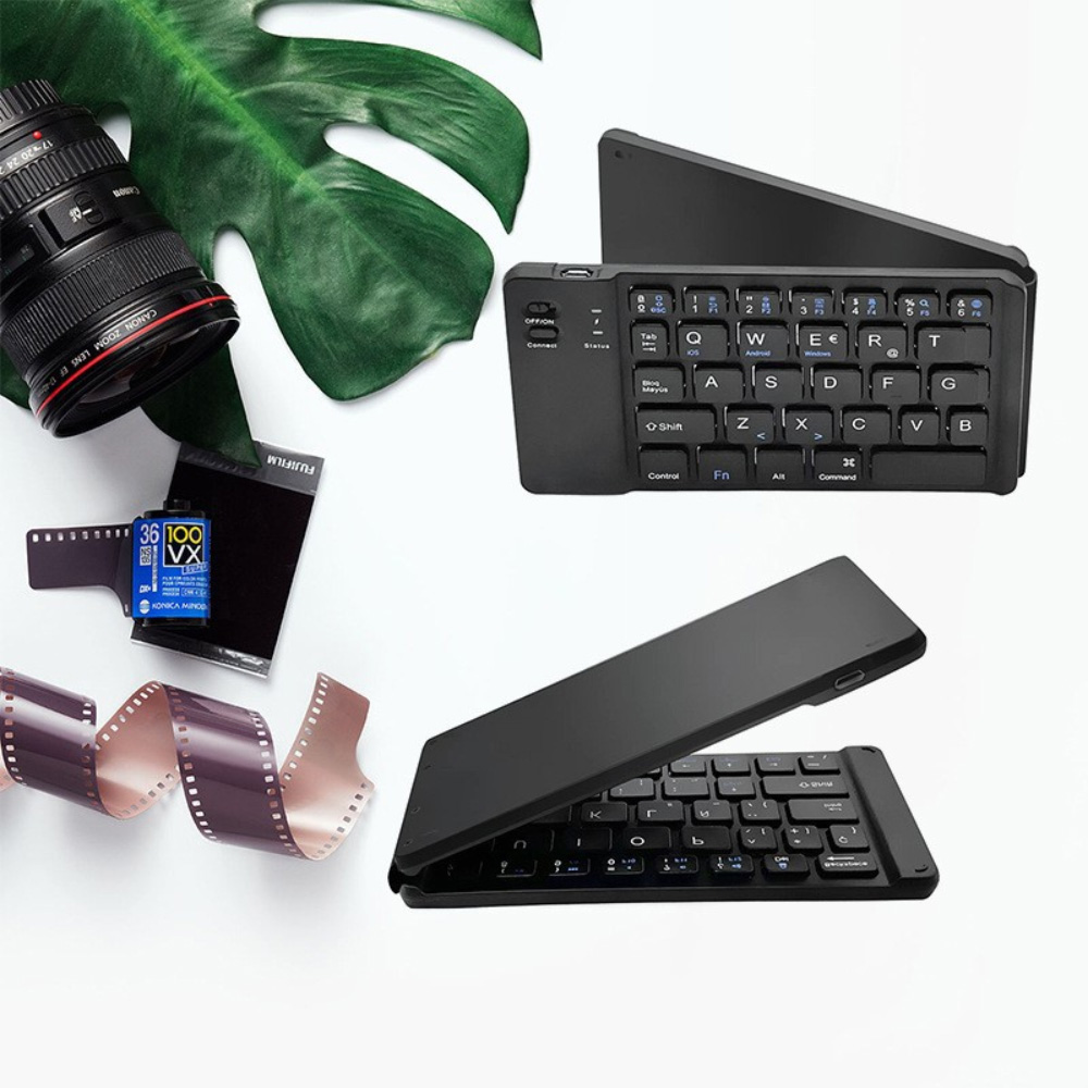 Kameraobjektiv, Filmrolle, SD-Karte und faltbare Tastatur auf weißem Hintergrund.