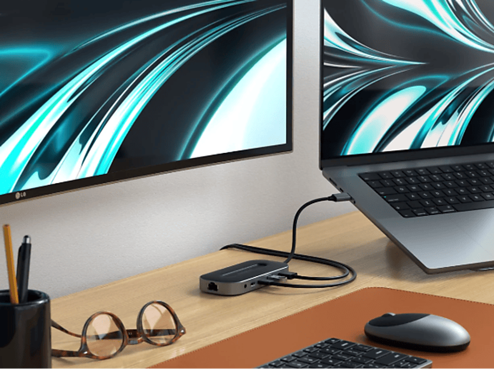 Ein Laptop- und Monitor-Setup mit Dockingstation, Brille und Maus auf einem Schreibtisch.