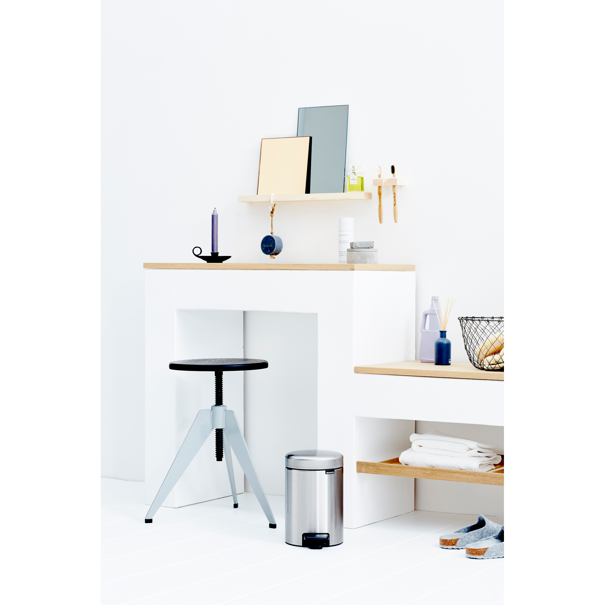 Helles Badezimmer mit Hocker, Mülleimer, Regal und Handtüchern.