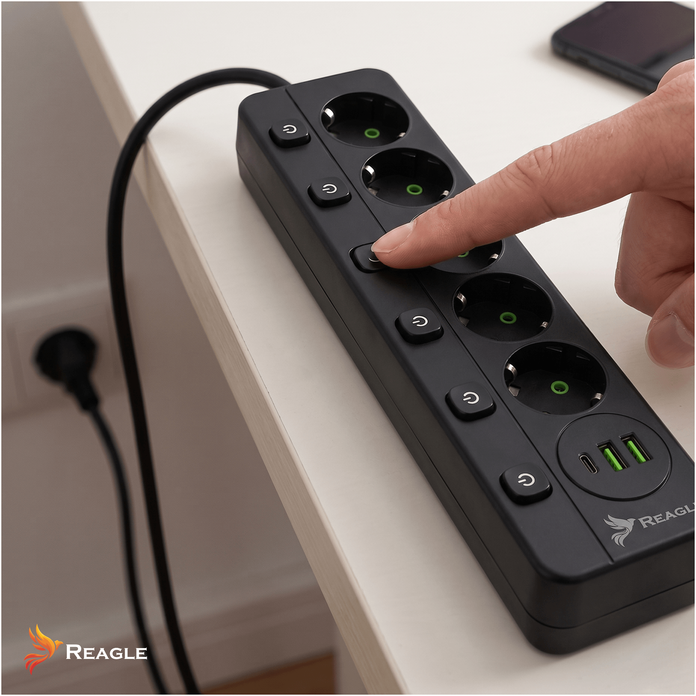Un dedo presiona un botón en una regleta negra con puertos USB. Un enchufe está en la pared.