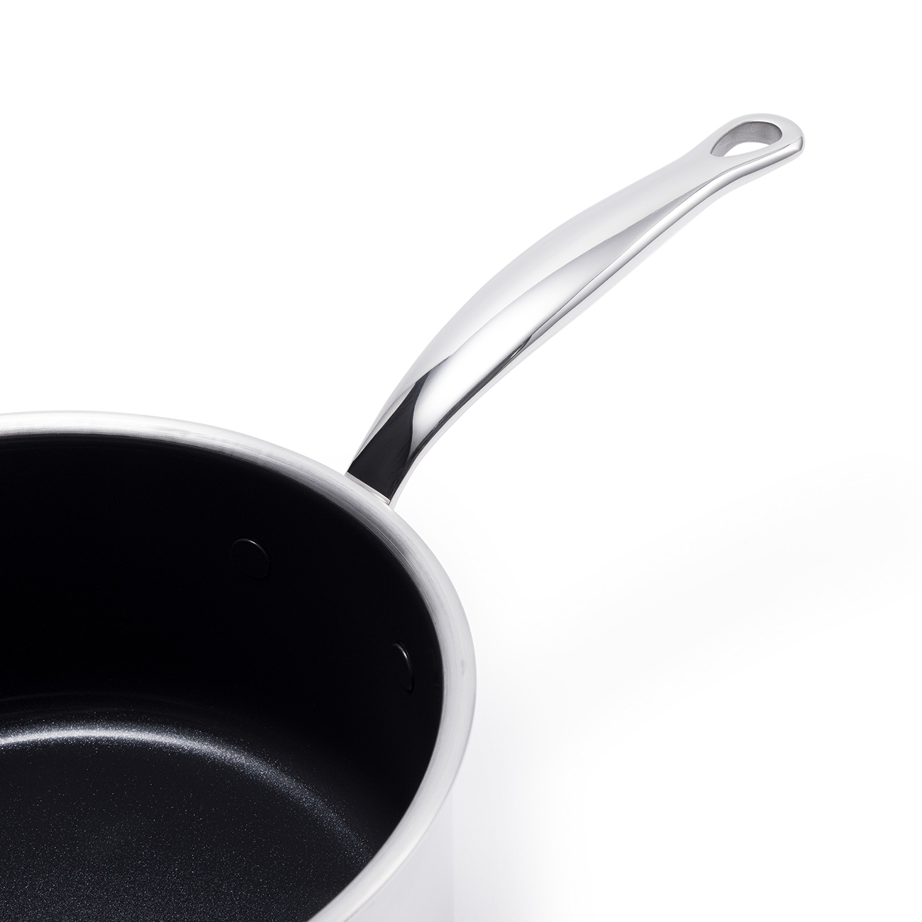 Primer plano de una sartén plateada con interior negro y mango largo sobre fondo blanco.