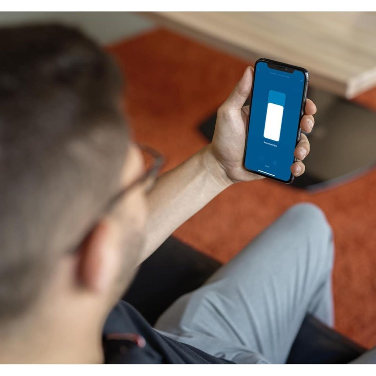 Mann hält ein Smartphone, das eine Helligkeitssteuerung zeigt.