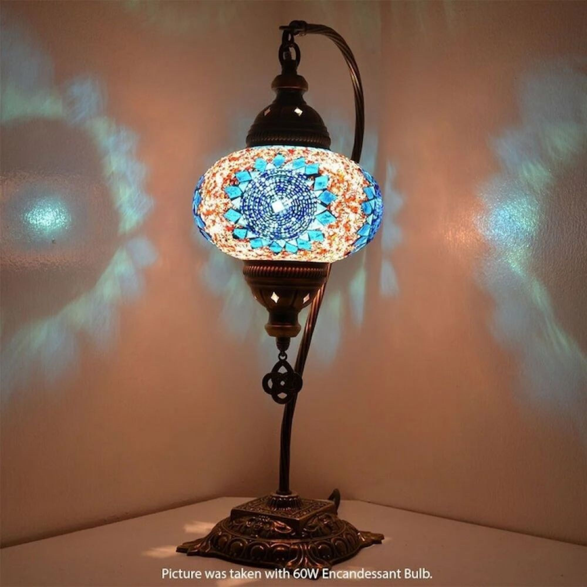 Eine Mosaik-Tischlampe mit blauem und orangefarbenem Glas wirft Lichtmuster an die Wand.