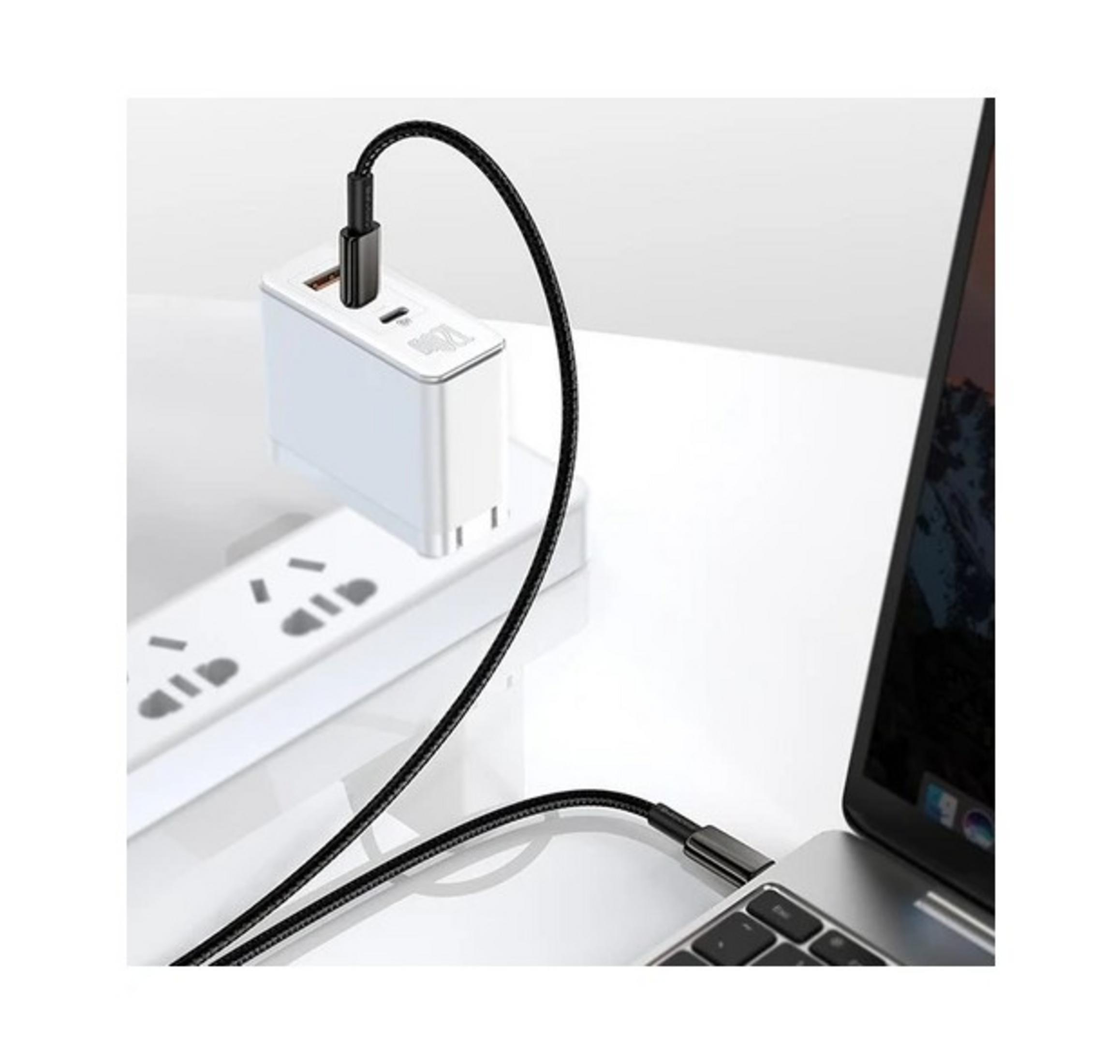 A white charging brick charges a laptop via a black cable plugged into a power strip.