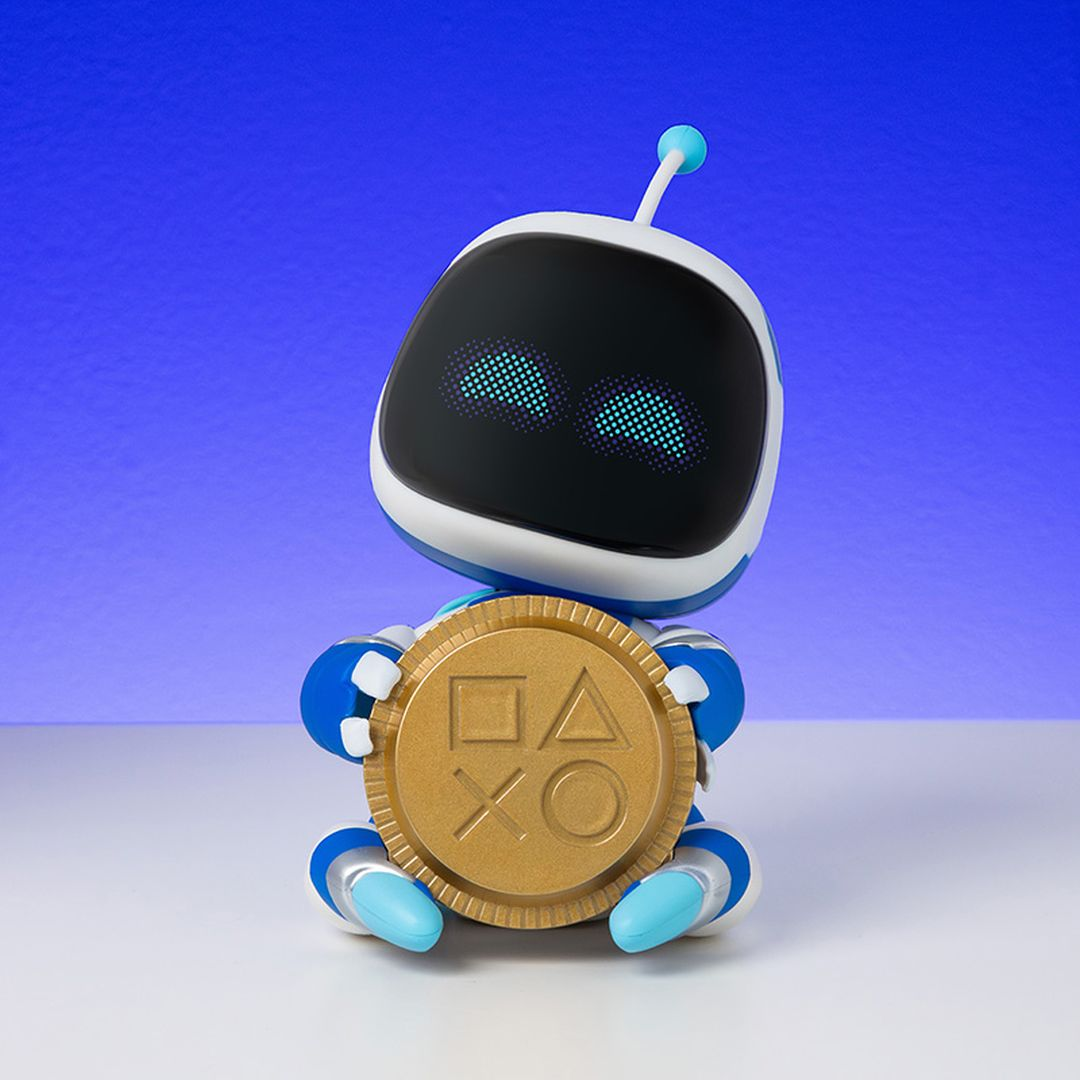 Niebieski i biały robot ze świecącymi oczami trzyma złotą monetę PlayStation.