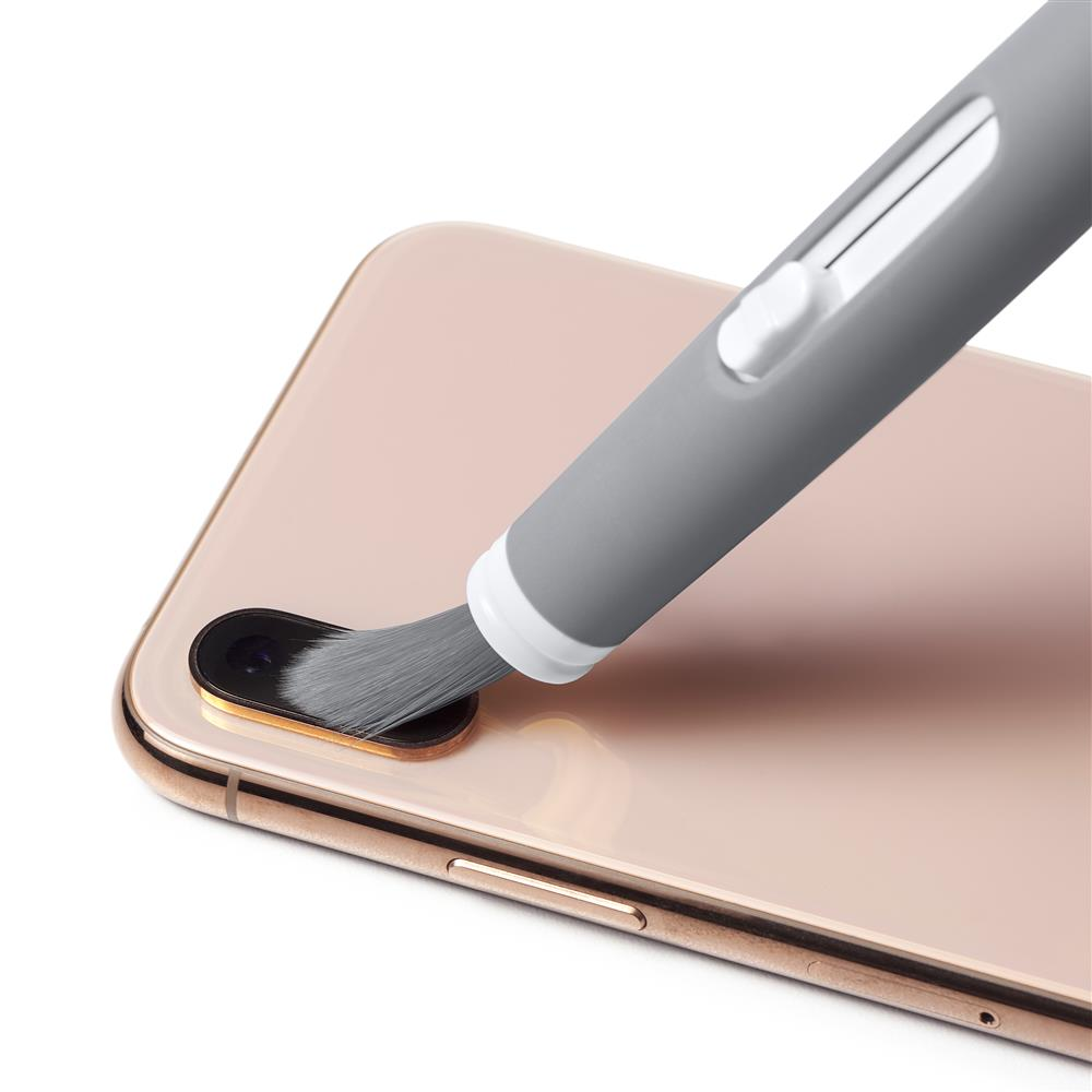 Gri temizleme kalemi, pembe altın rengi bir akıllı telefonun kamera lensini temizliyor.